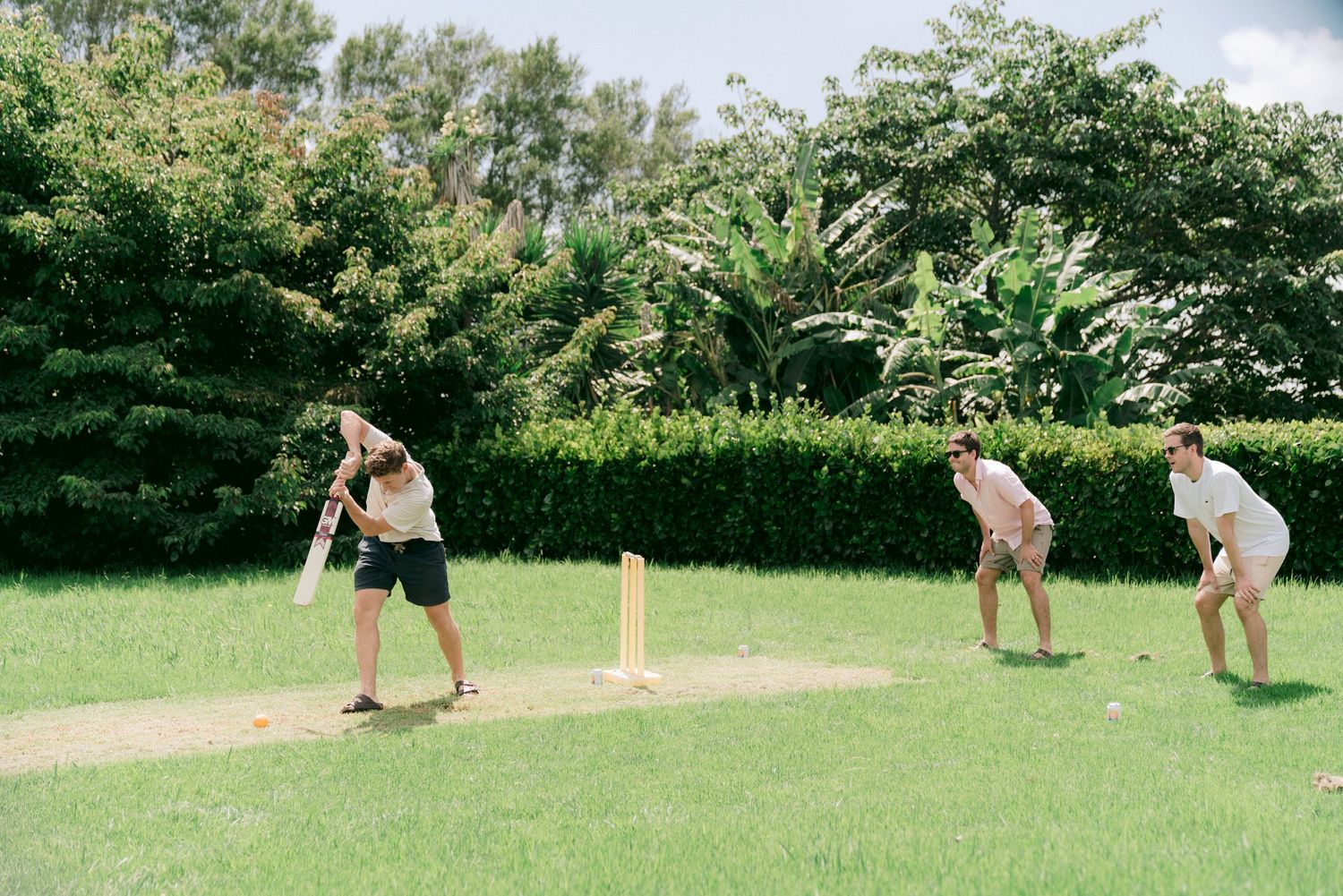 People playing outdoor lawn games in a green garden setting with wooden equipment.