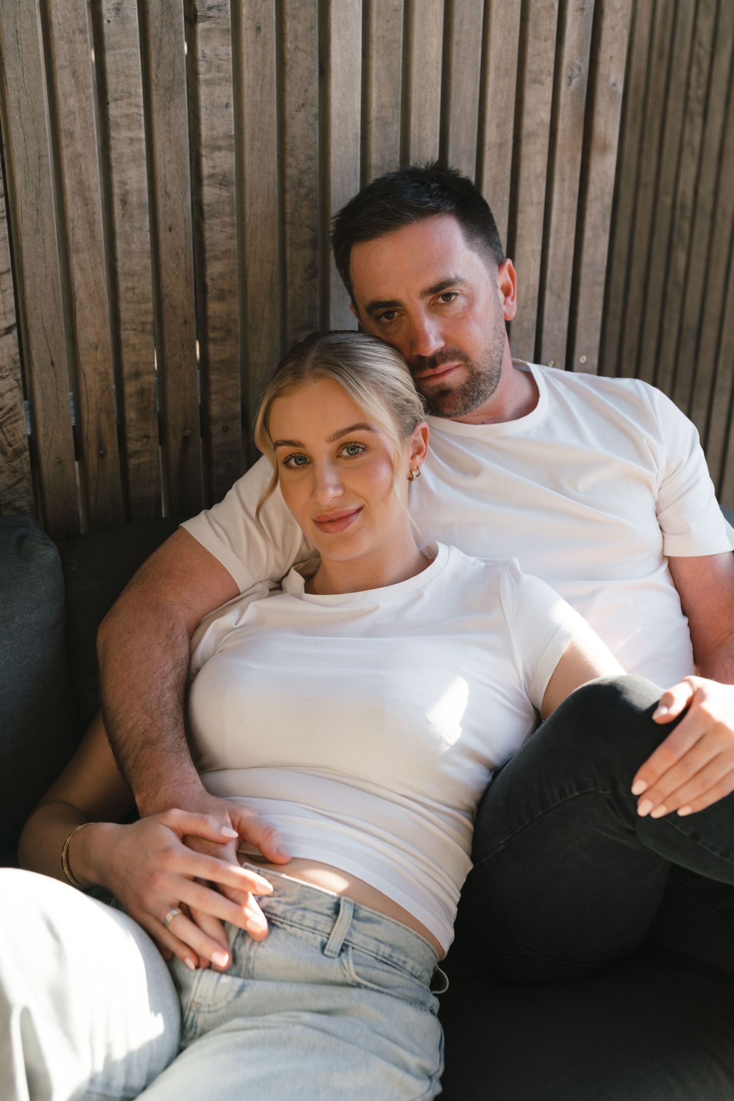 People relaxing together on a couch wearing white t-shirts and casual clothing.