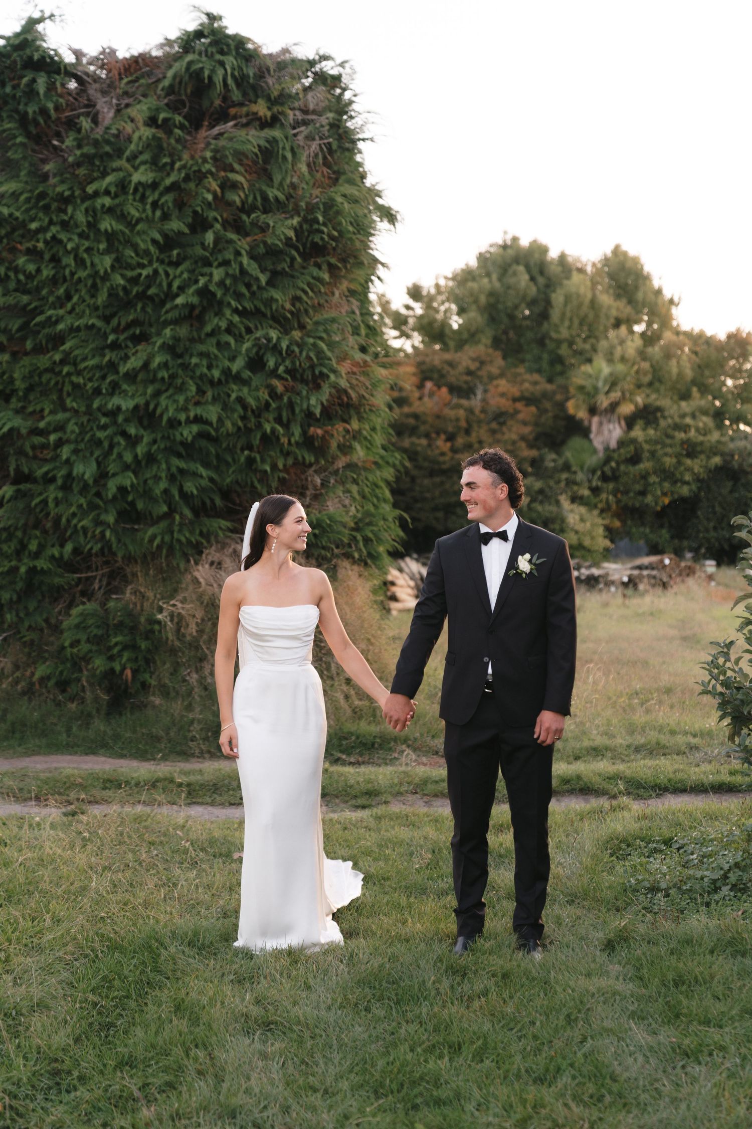 Newlyweds walk together through a scenic garden setting during their wedding day.