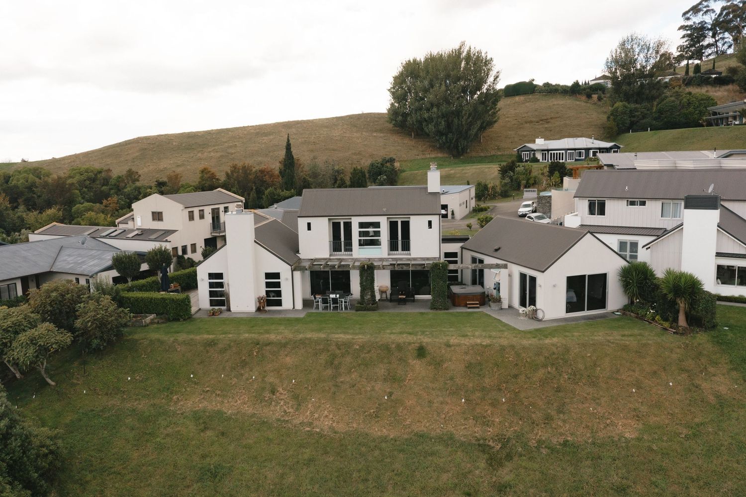 Panoramic view of modern white residential homes nestled on rolling green hillsides in a suburban development.