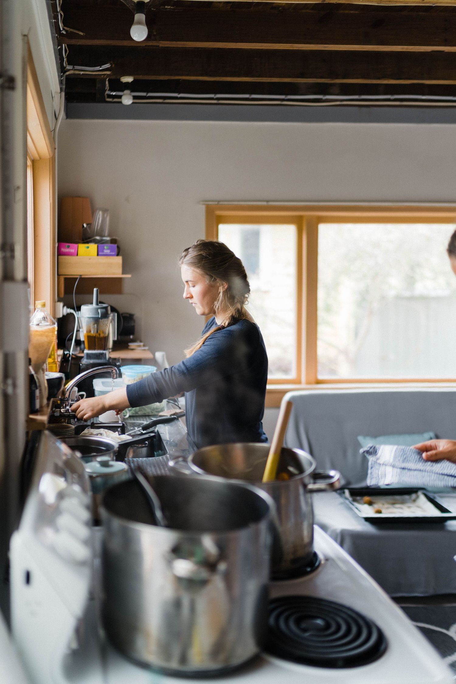 People work in a sleek commercial kitchen with black countertops and natural lighting from large windows.