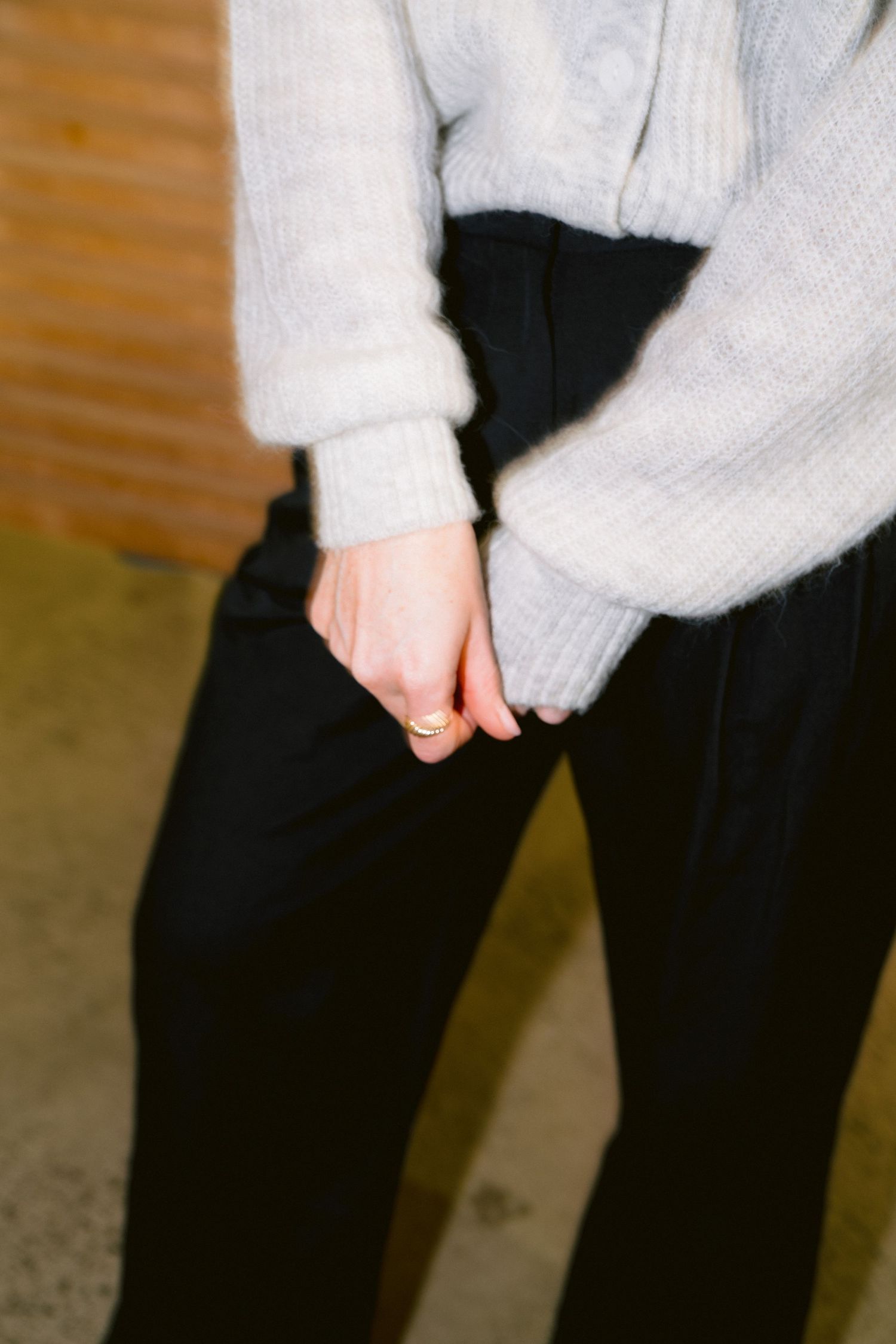 Person wearing cozy white sweater and black pants showing off winter fashion style from torso down.