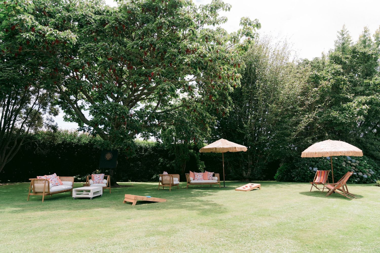Outdoor garden setting with lounge furniture and parasols arranged on a green lawn.