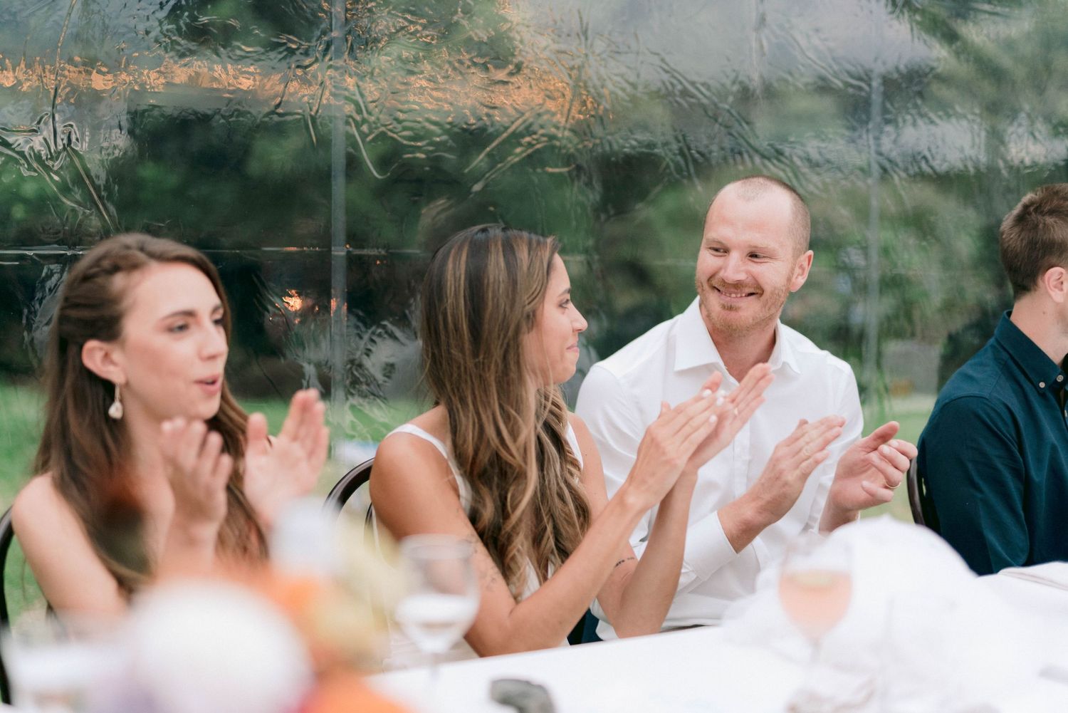 Wedding guests enjoying speeches and entertainment at an outdoor reception.