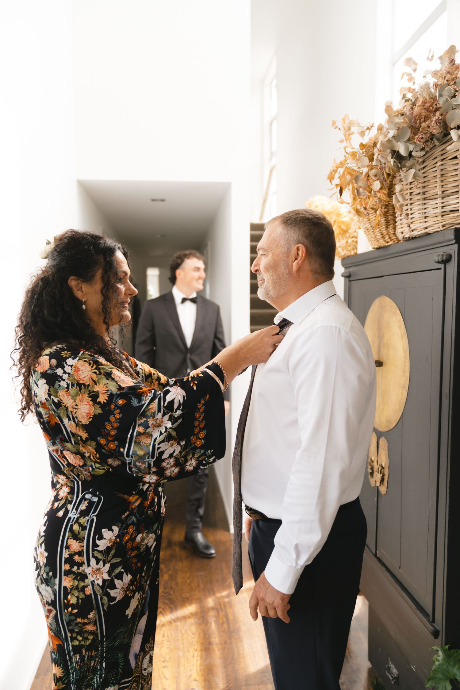 Wedding preparation scene with people in formal attire getting ready in a bright interior.
