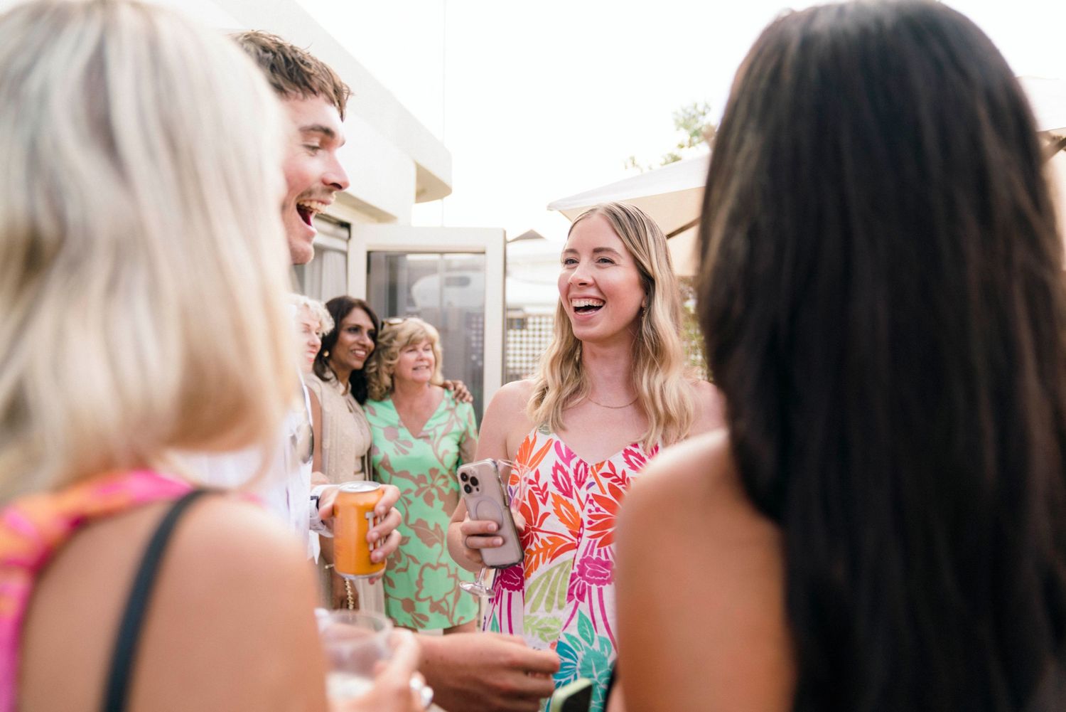A joyful group of guests share animated conversation at a summer party.