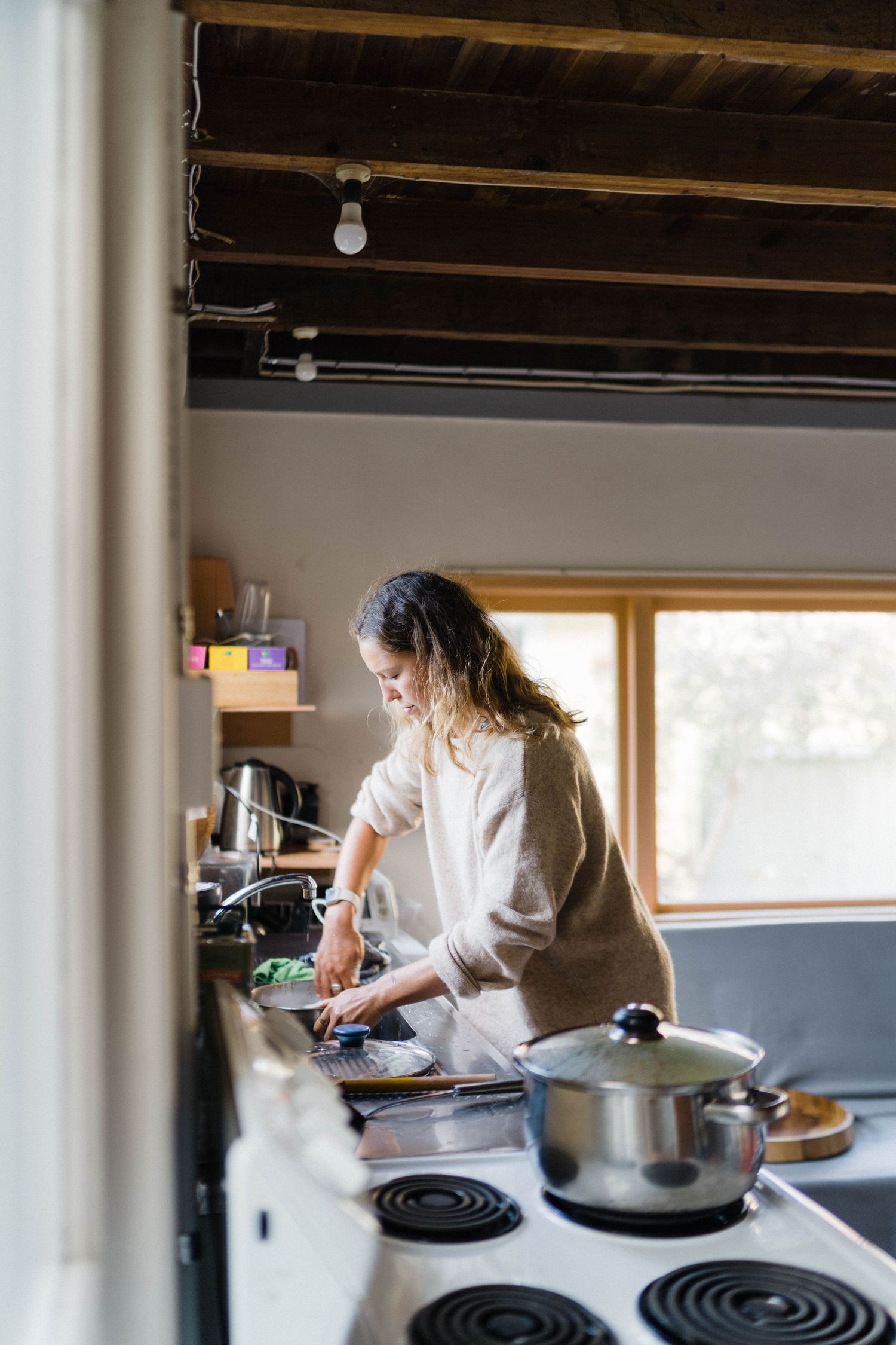 Cooking in a modern kitchen with exposed wooden ceiling beams and natural lighting.