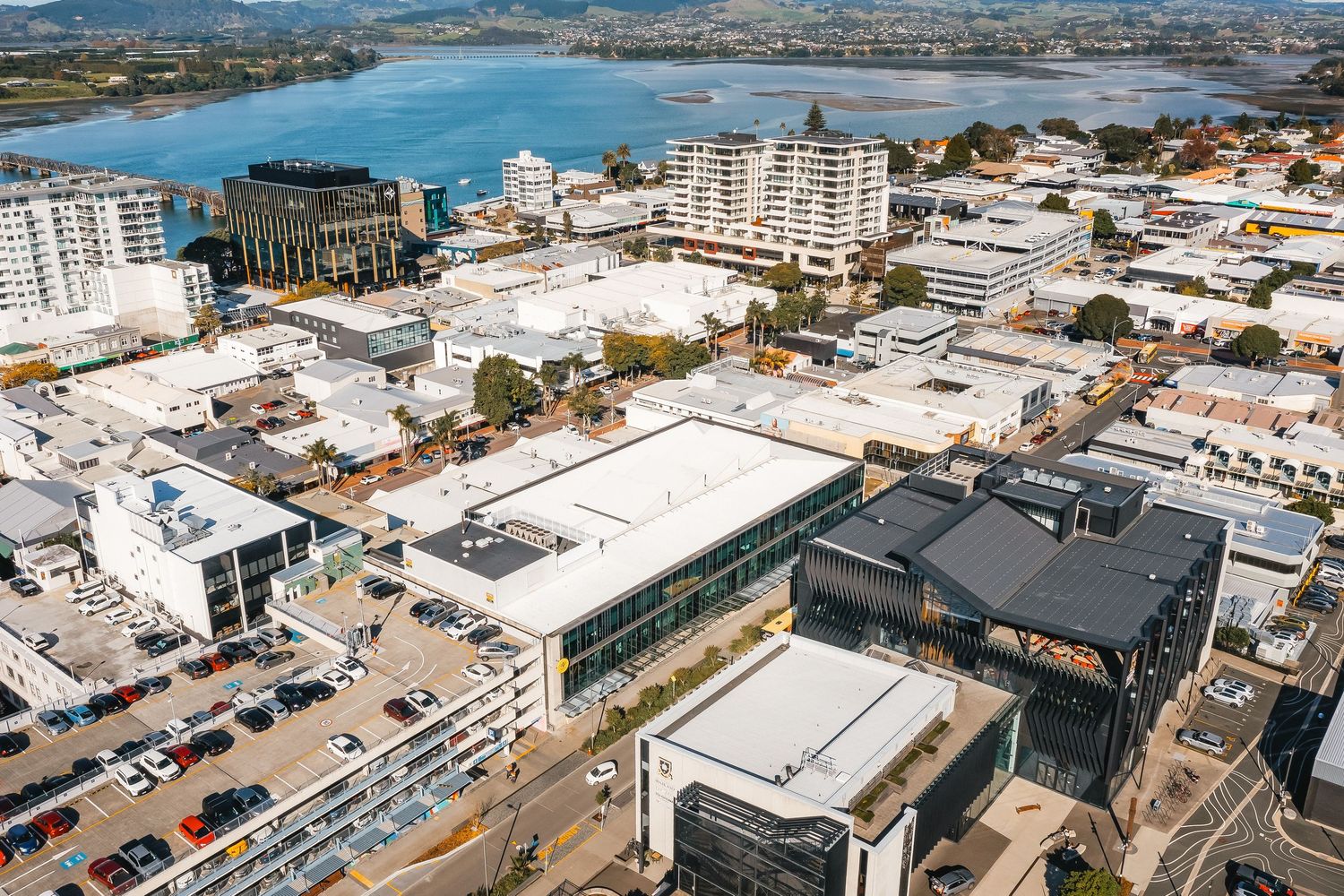 Aerial view of coastal city skyline with buildings and waterfront development along harbor.