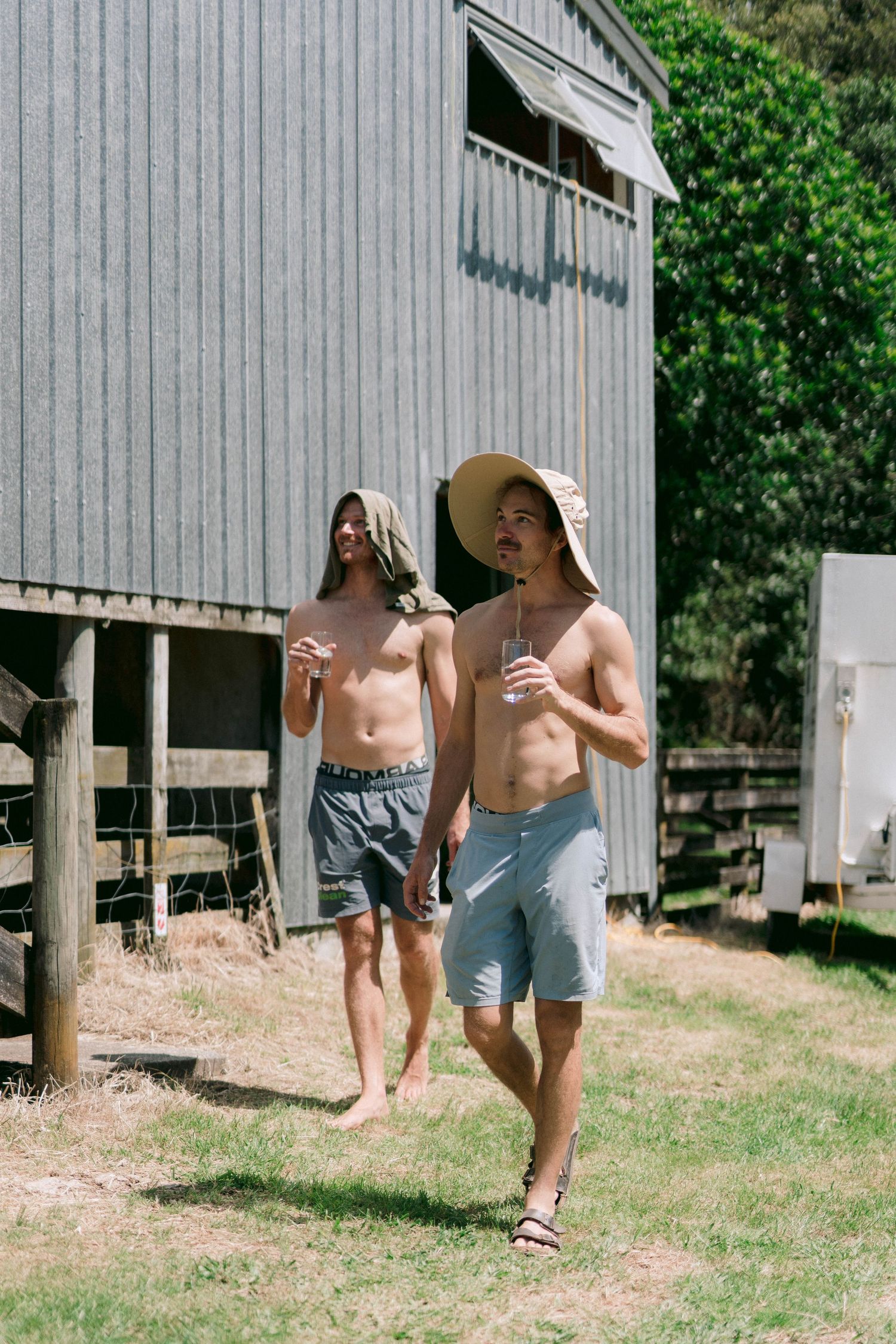 Friends enjoy a sunny day outdoors near rustic wooden buildings and natural surroundings.