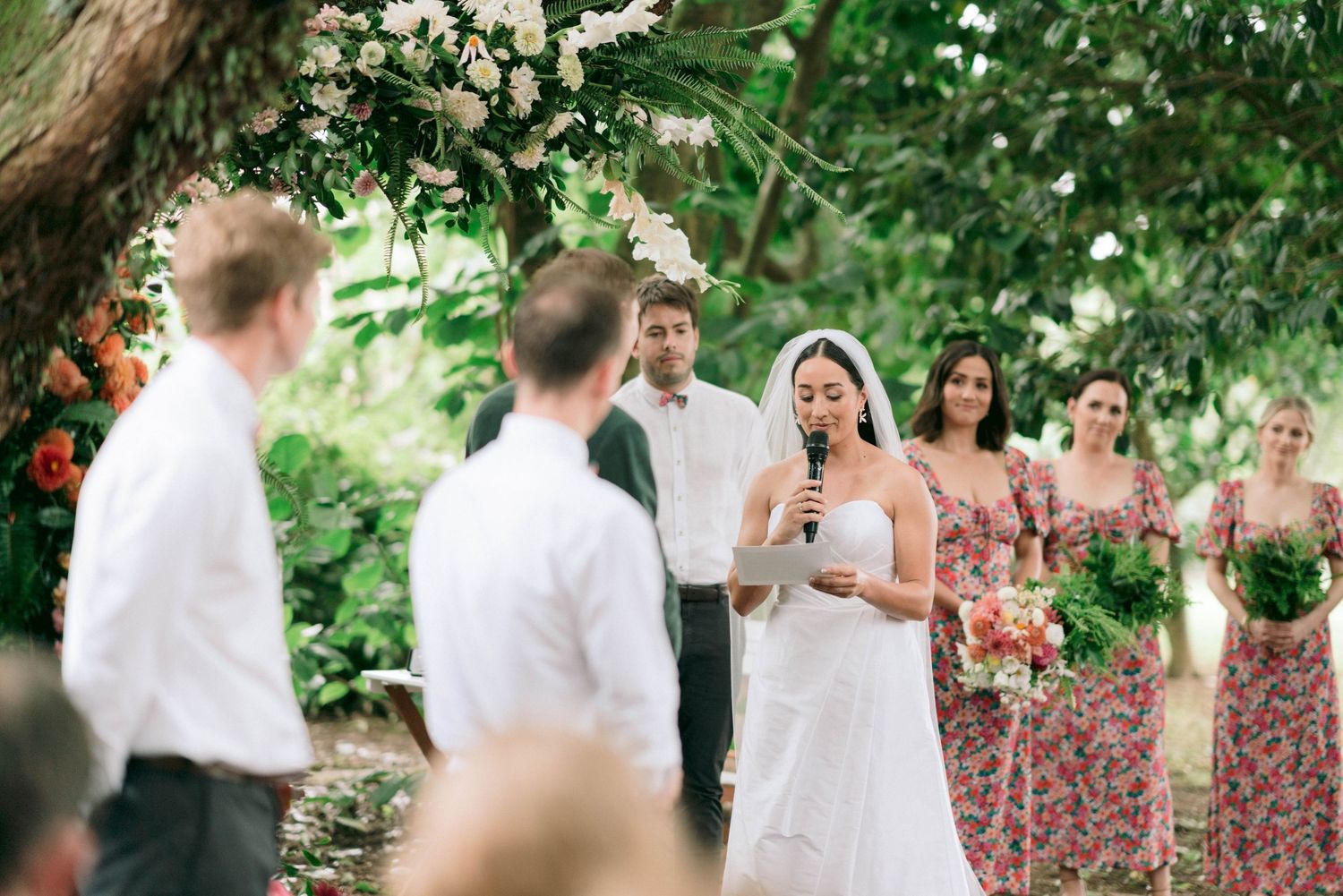 Wedding celebration with bridal party under garden trees.