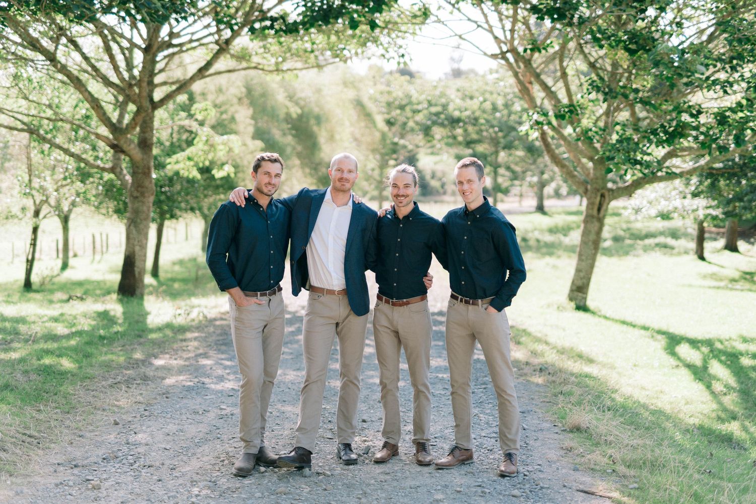 Wedding party members arranged in formal groups for outdoor portraits in a natural setting.