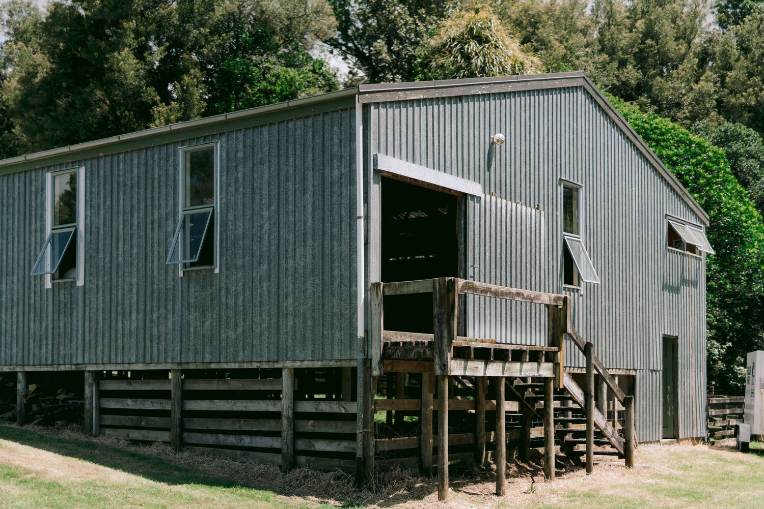 Exterior view of a modern gray barn-style building with wooden decks in a natural setting.