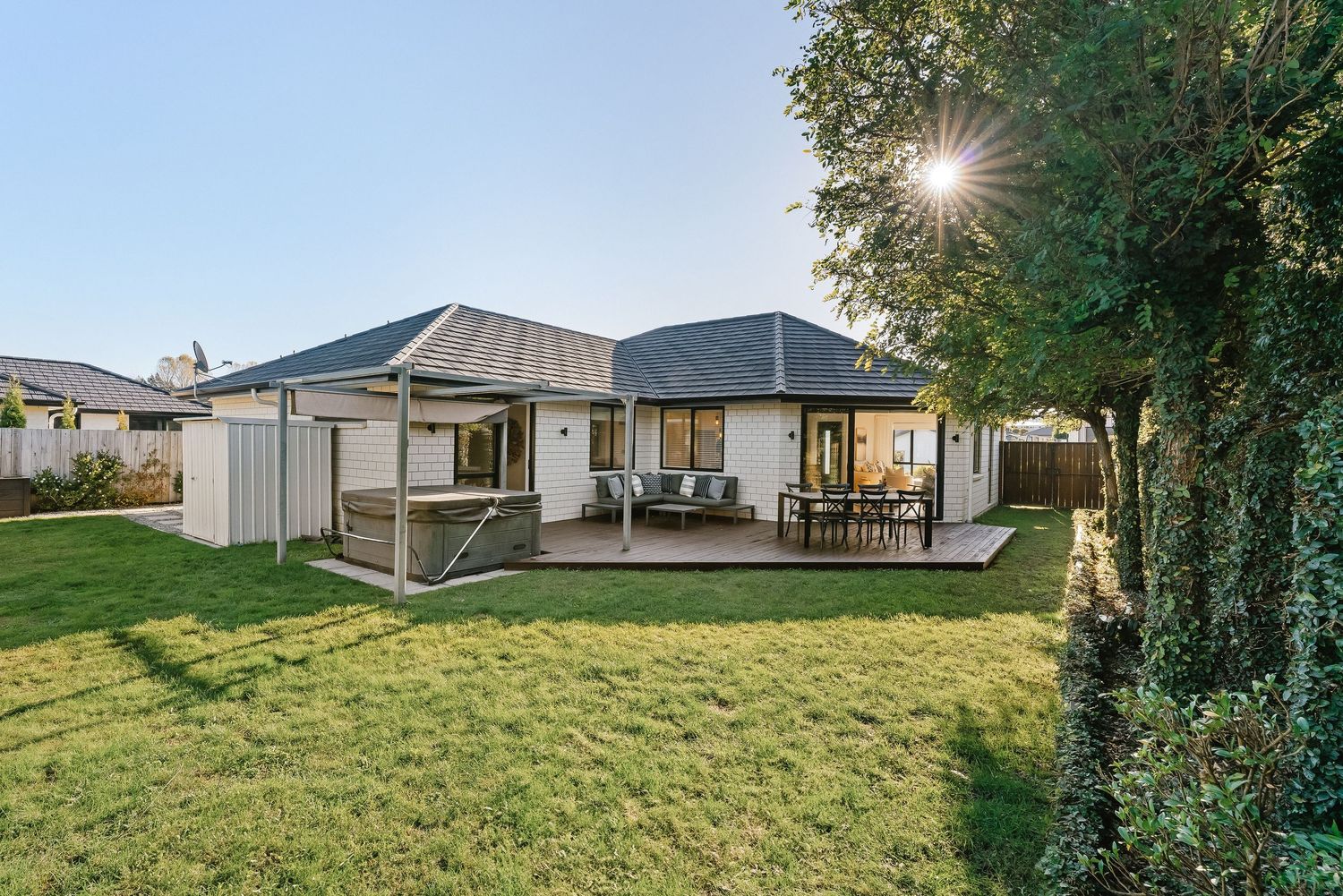 Single-story modern home with grey exterior and manicured lawn lit by evening light.