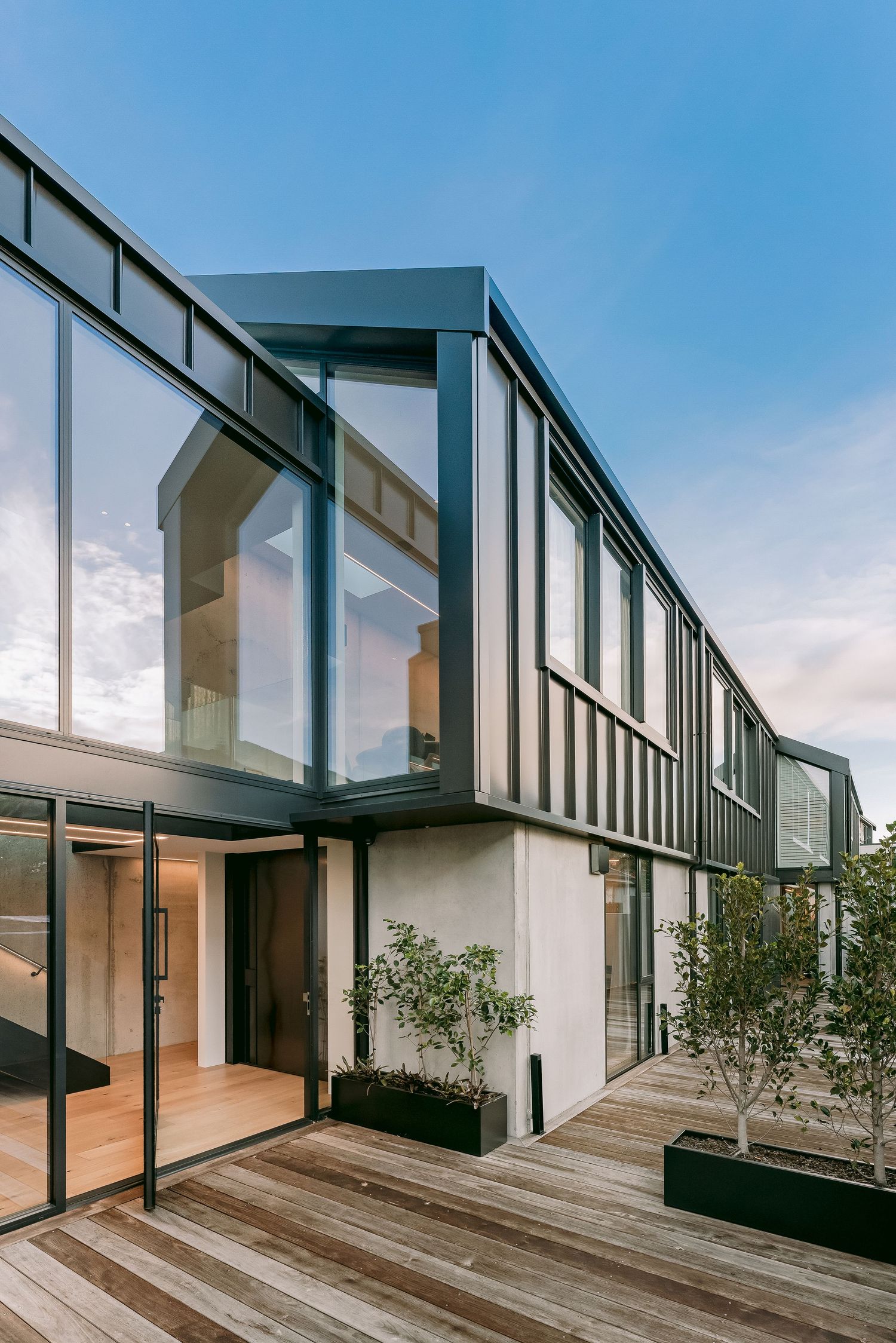 Contemporary residential building featuring floor-to-ceiling windows and wooden deck terrace with minimalist design.