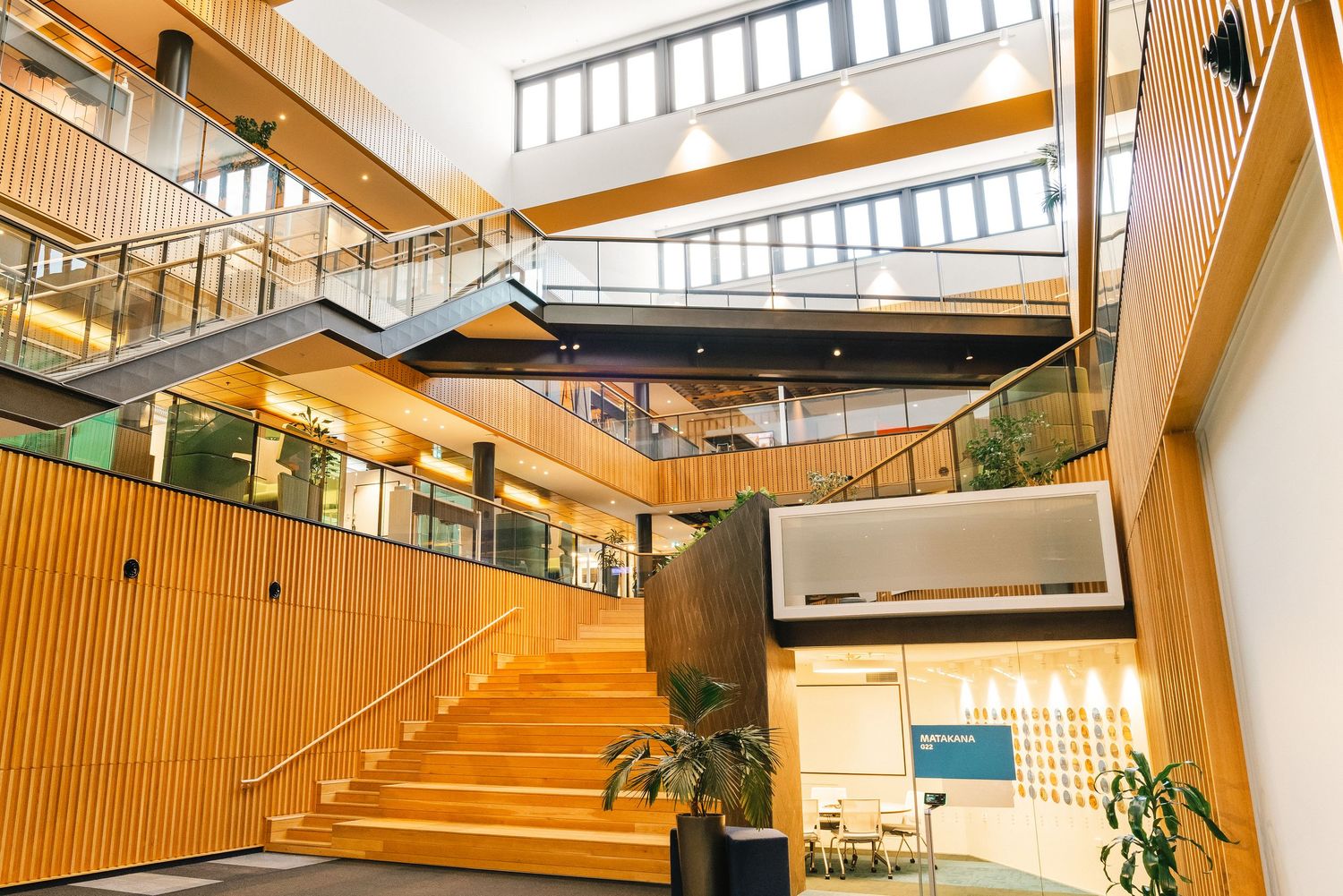 Modern wooden staircase with horizontal slats and natural lighting in an open office building's interior.