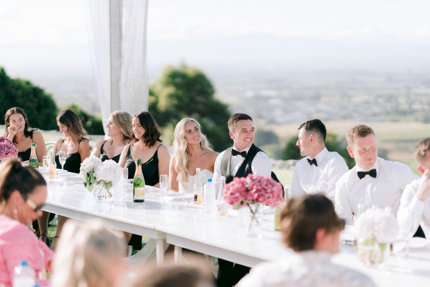Elegant long table wedding reception setup under white tent with mountain views.