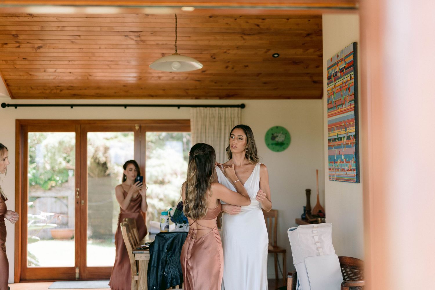 Light-filled room with wooden ceiling beams and rustic decor where women gather before an event.