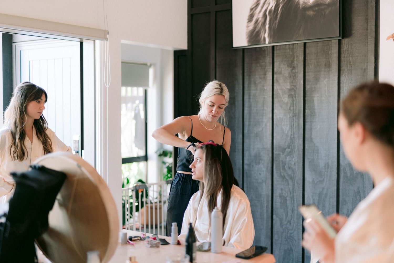Styling professionals work on hair preparation in a modern salon with dark wooden walls.