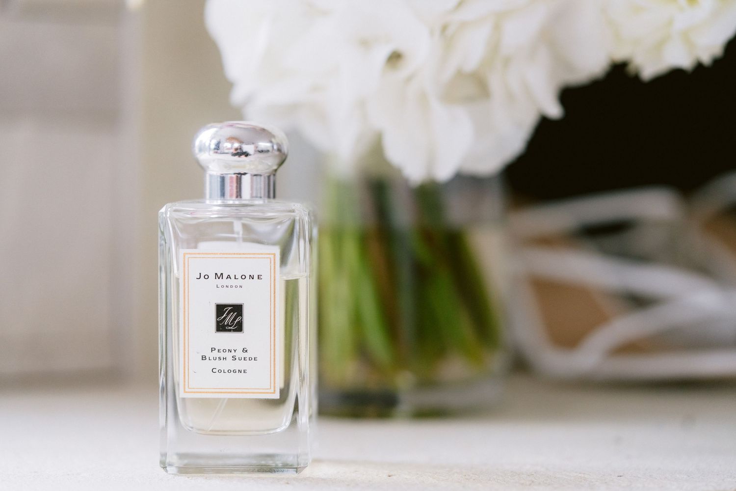 Elegant glass perfume bottles arranged in a row with white floral decor on a light-colored surface.