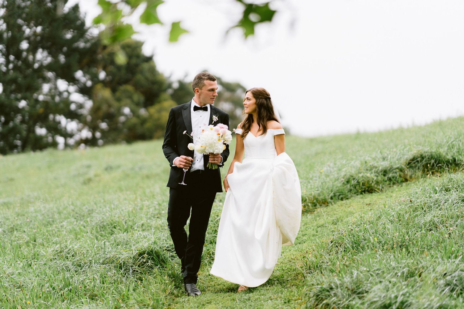 Couple taking romantic portraits on a lush green hillside.