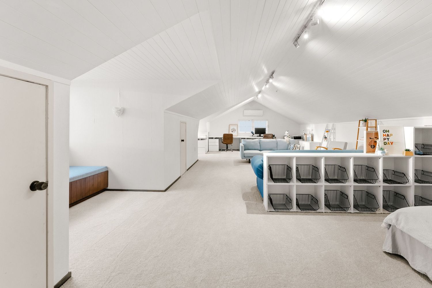 Long white attic space with track lighting and built-in storage solutions.