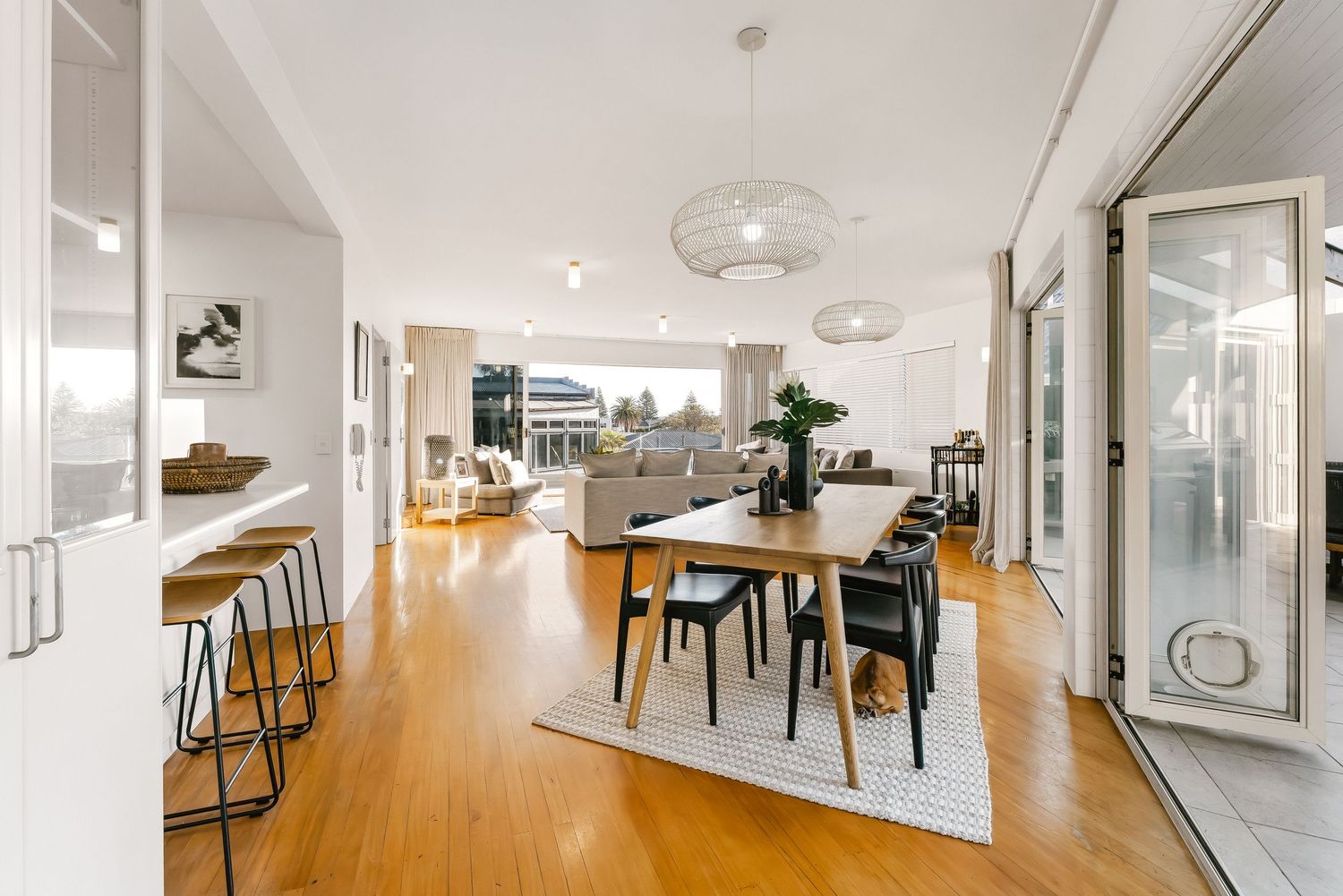 Open concept living space with hardwood floors, modern dining area, and contemporary lighting fixtures.