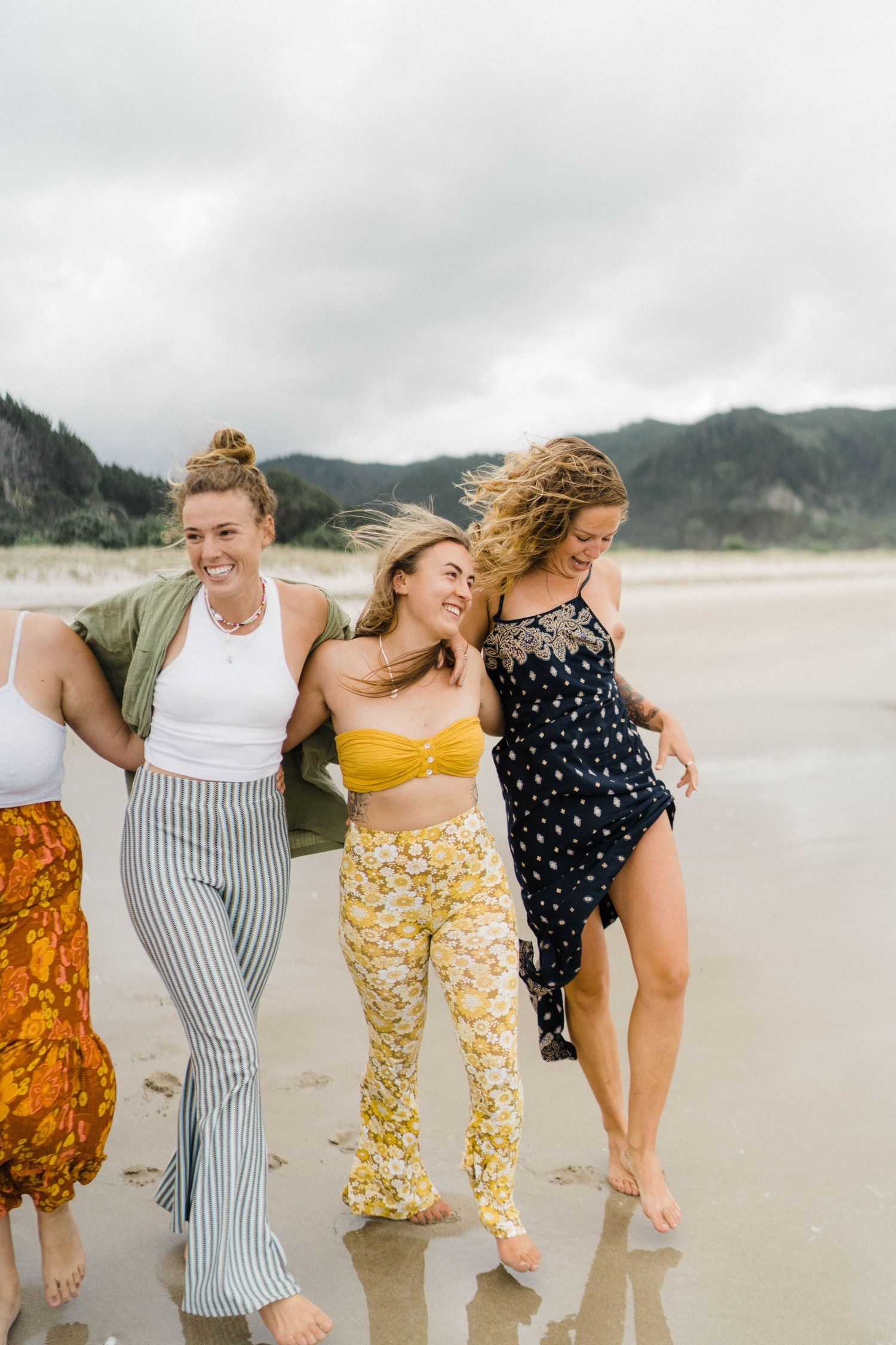 Friends laughing together while walking along a misty beach.
