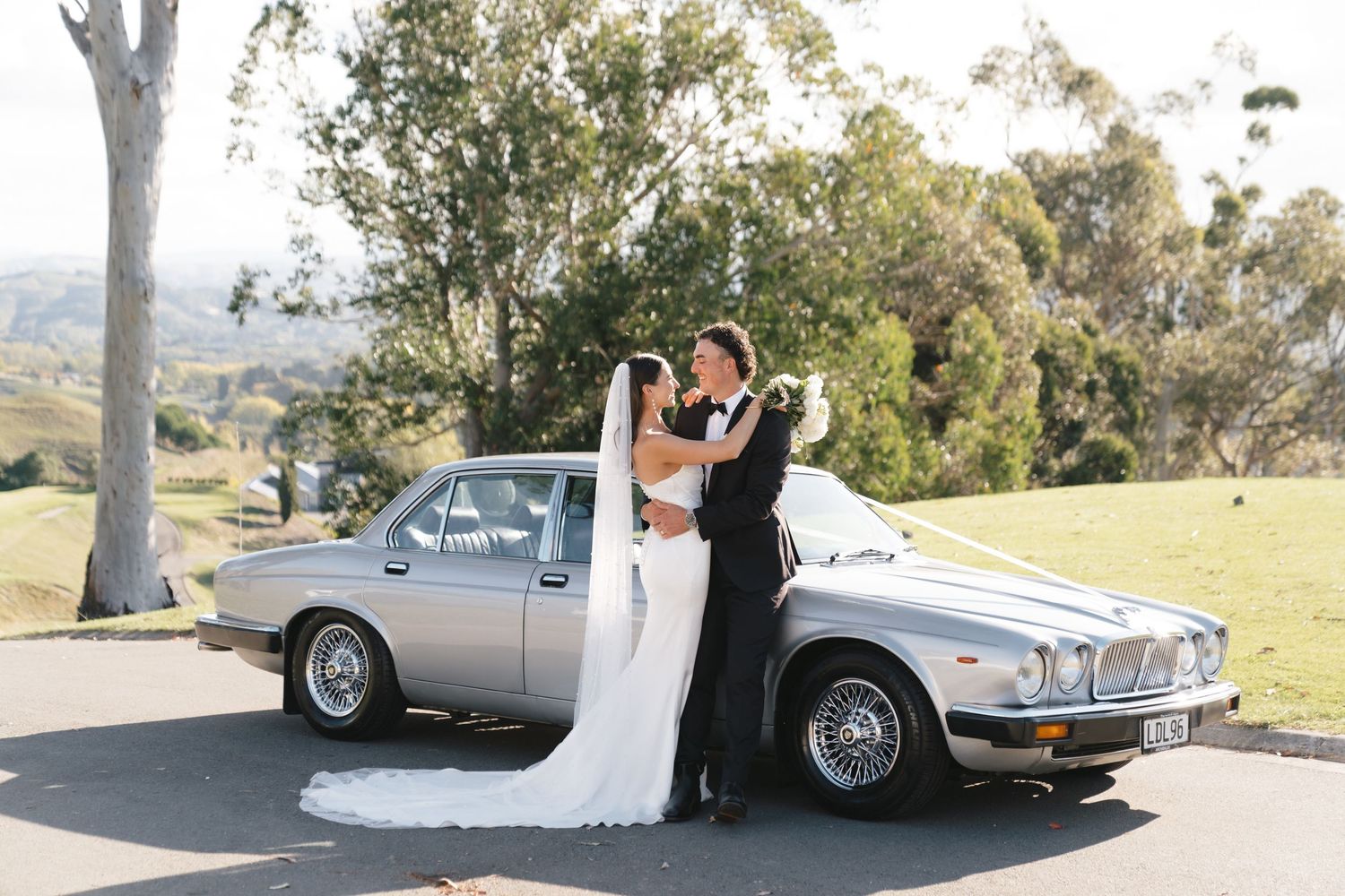 Classic silver vintage car parked outdoors for wedding transportation.