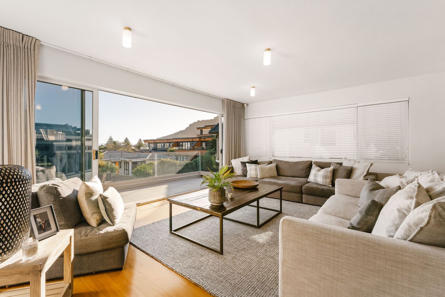 Bright living room with panoramic windows features gray sectional sofa and minimalist decor.