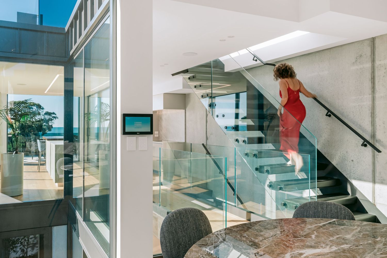 Contemporary multi-level home interior featuring glass staircase, marble floors and open concept design.