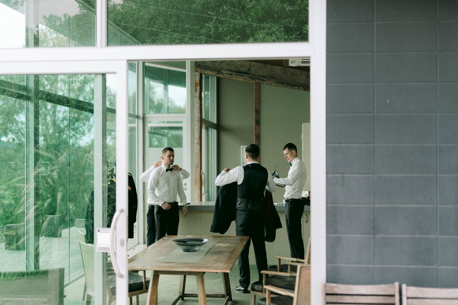 Group preparing in modern room with floor-to-ceiling windows and casual atmosphere.