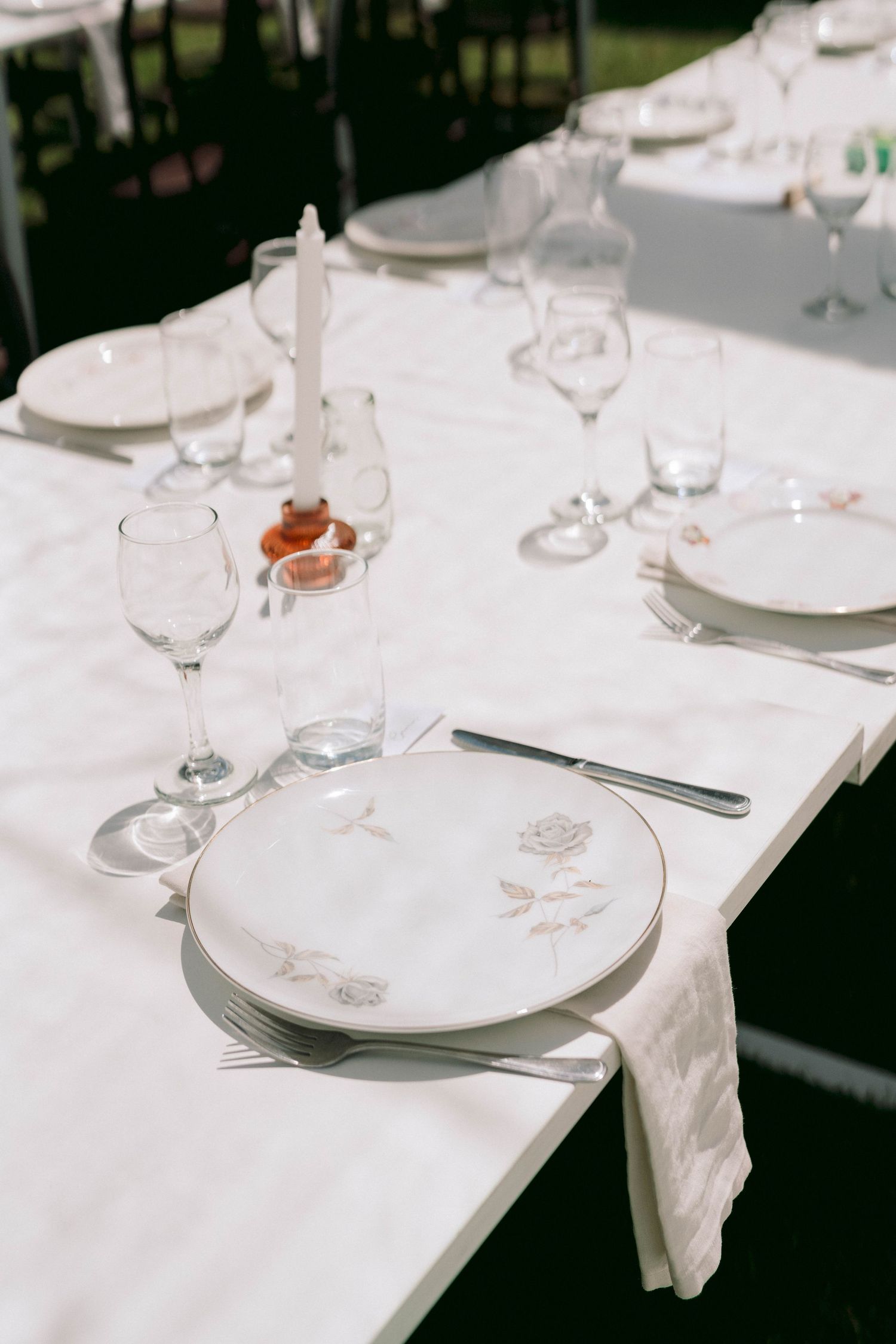 Elegant wedding table settings with white linens, crystal glasses, and fine china plates arranged formally.