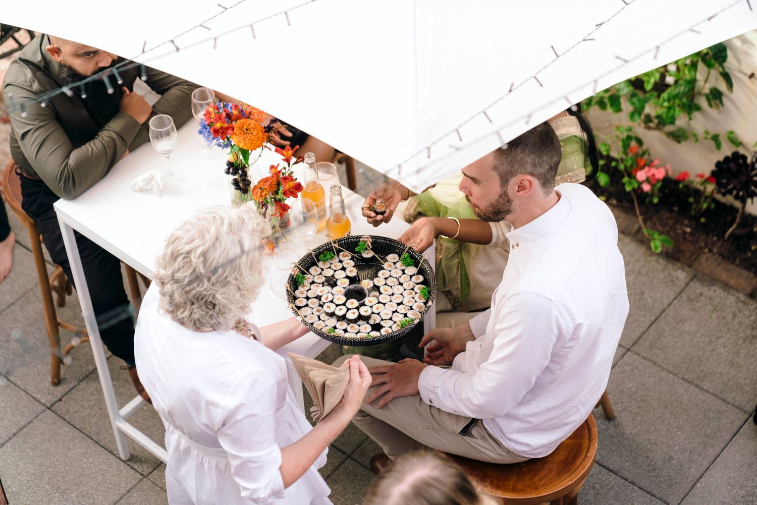 A decorated dessert is shared between guests at an outdoor dining table.
