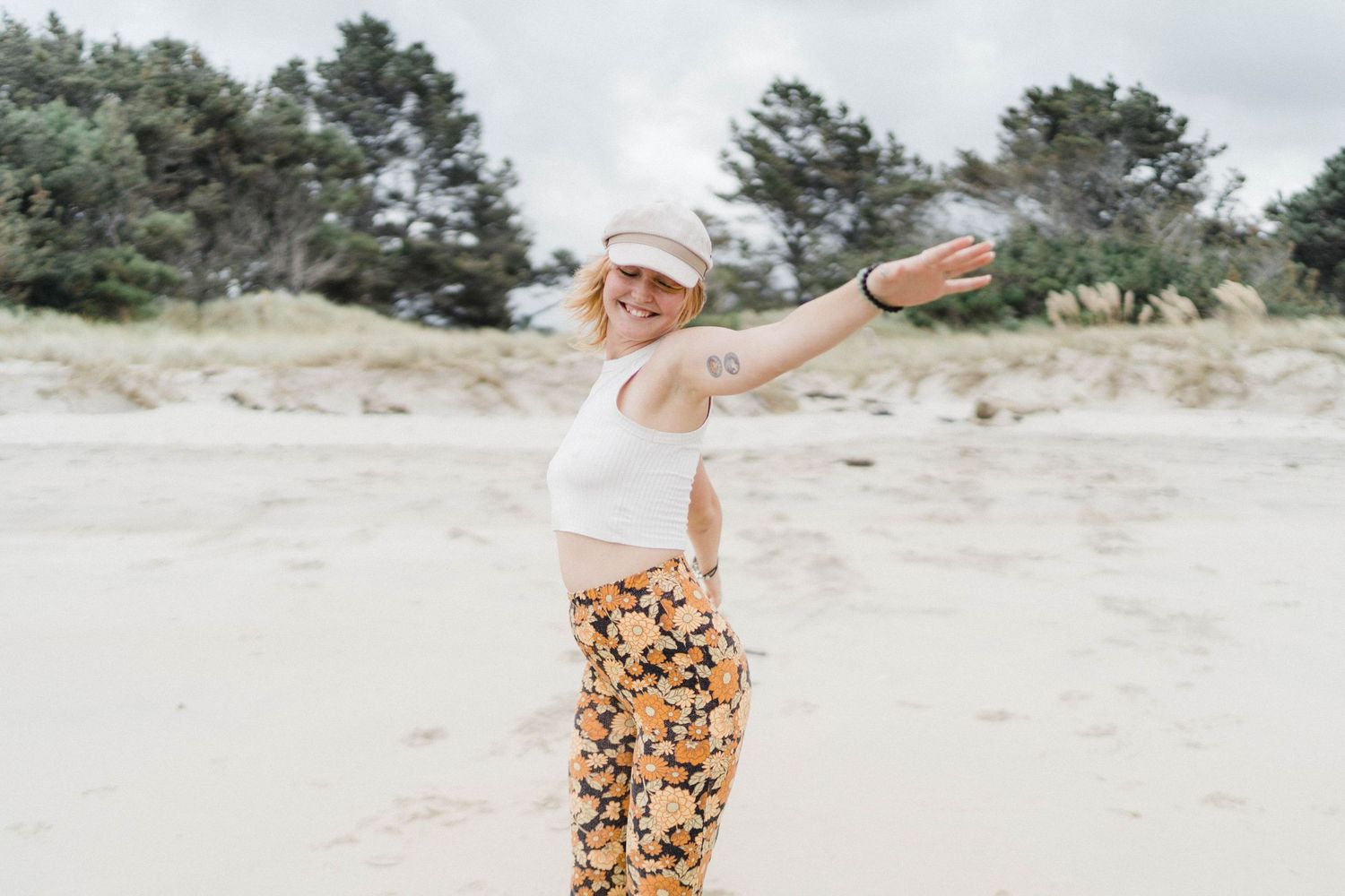 Joyful moment captured at sandy beach with coastal vegetation in background.