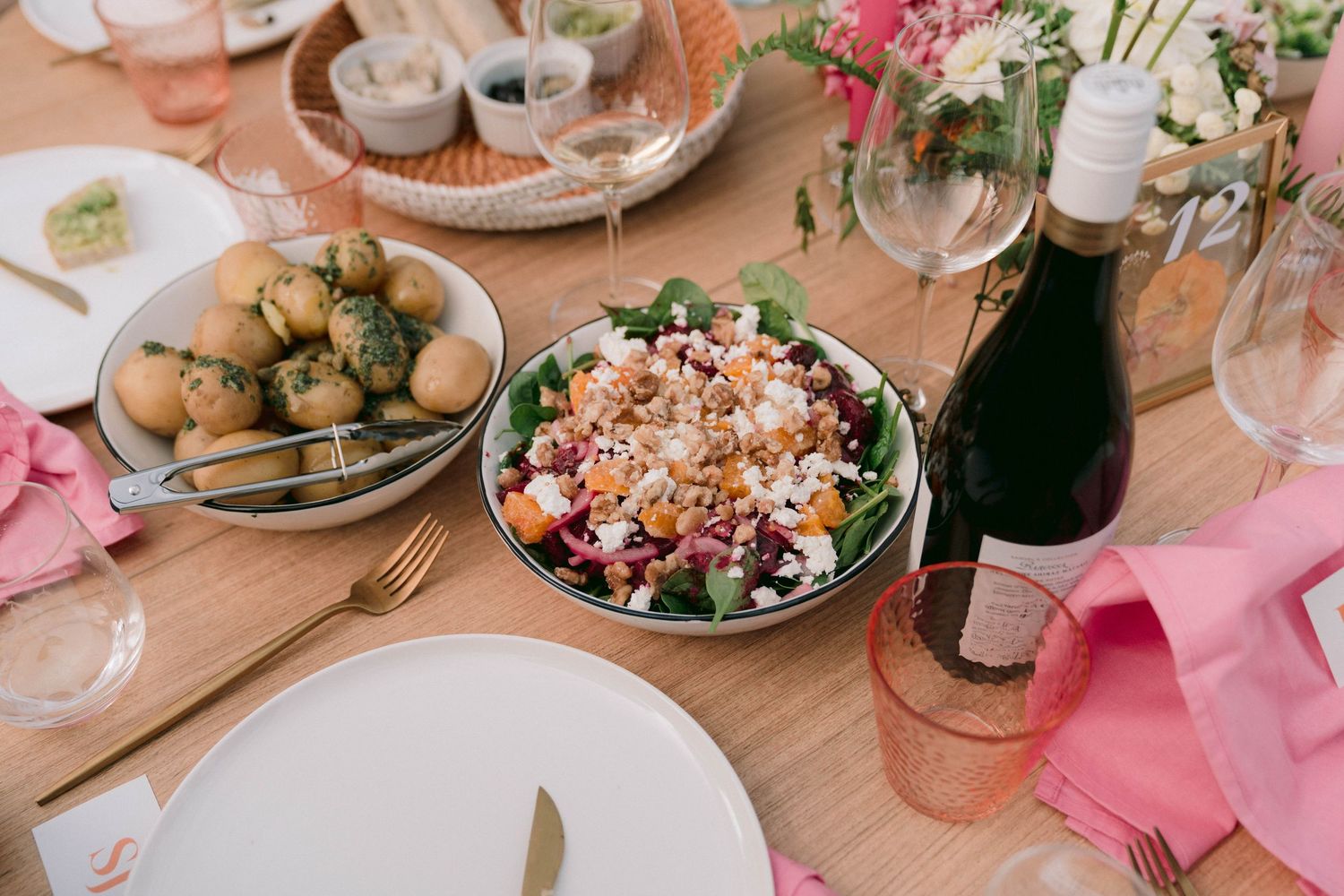 Elegant wedding reception table with pink accents and gourmet food displays.