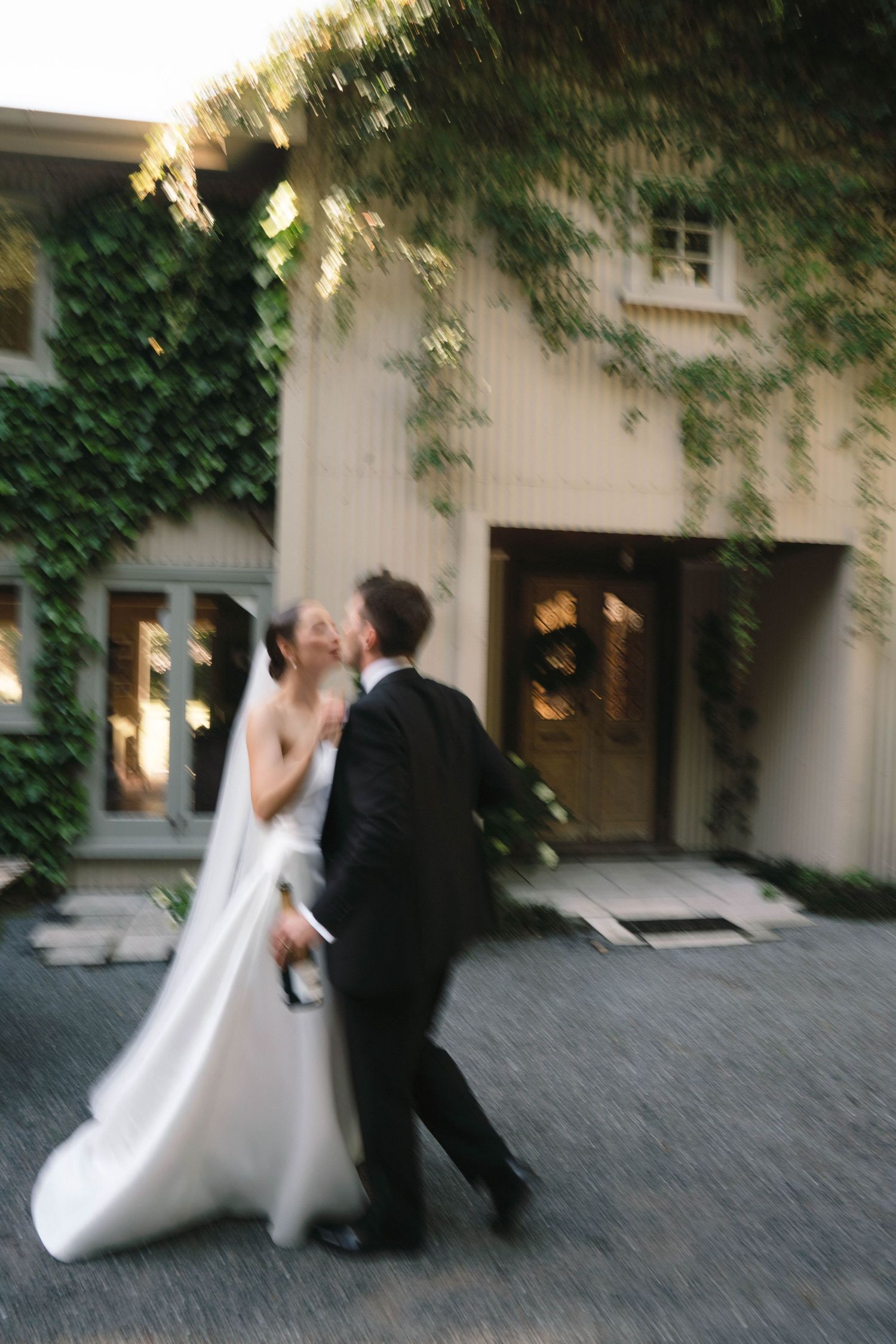 A couple sharing an intimate moment outside an ivy-covered building.