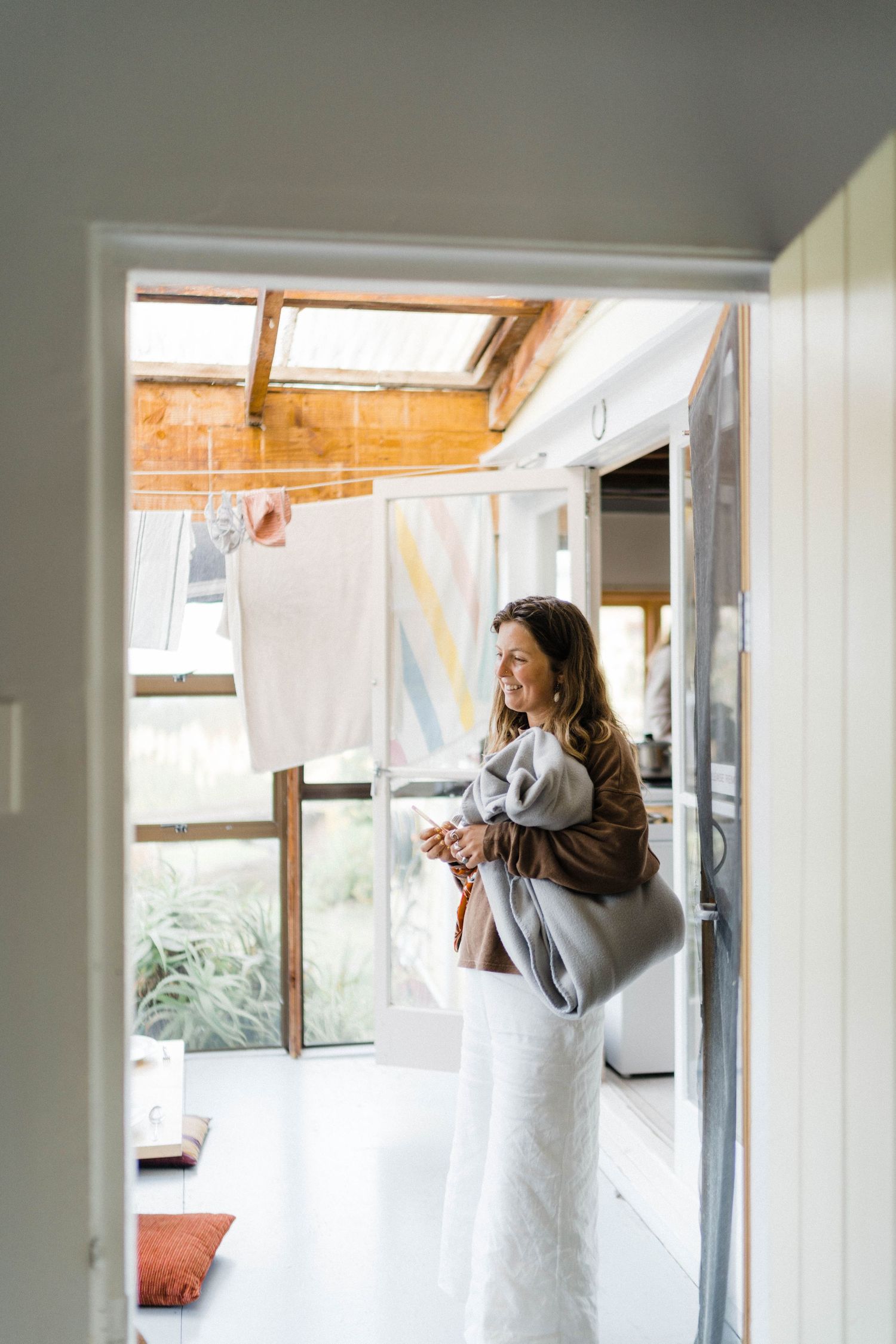 Natural light streams through a skylight window as a person in a gray coat checks their belongings in a bright interior space.