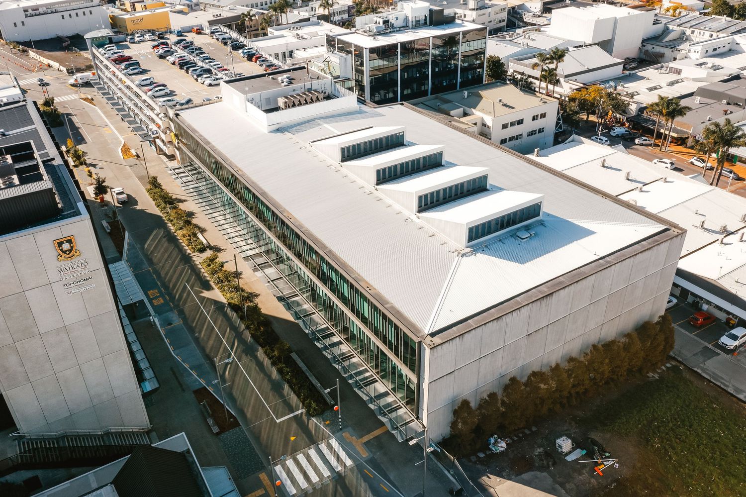 Modern industrial building with sawtooth roof design and skylights viewed from an aerial perspective.