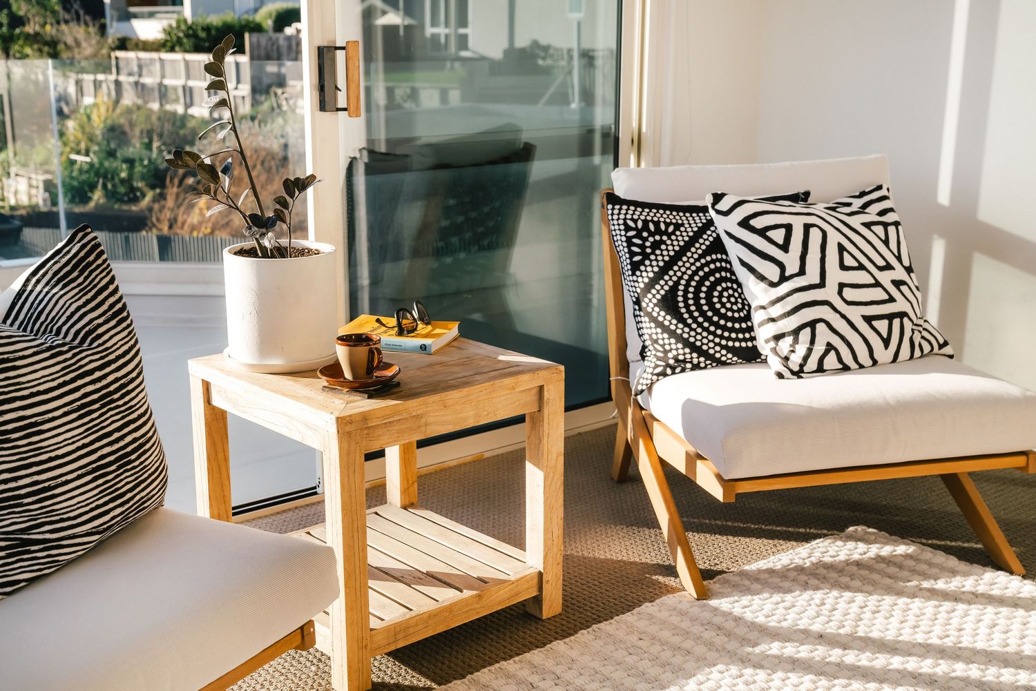 Modern patio furniture arrangement with geometric patterned cushions and wooden frame chairs.