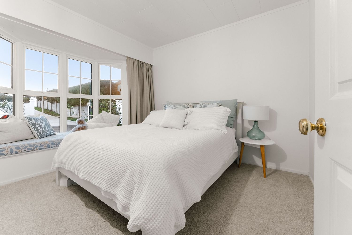 Serene white bedroom with large windows and coastal-inspired decor.