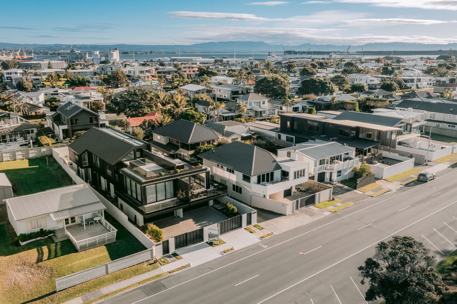 Aerial view of a residential neighborhood with modern houses and streets under blue skies.