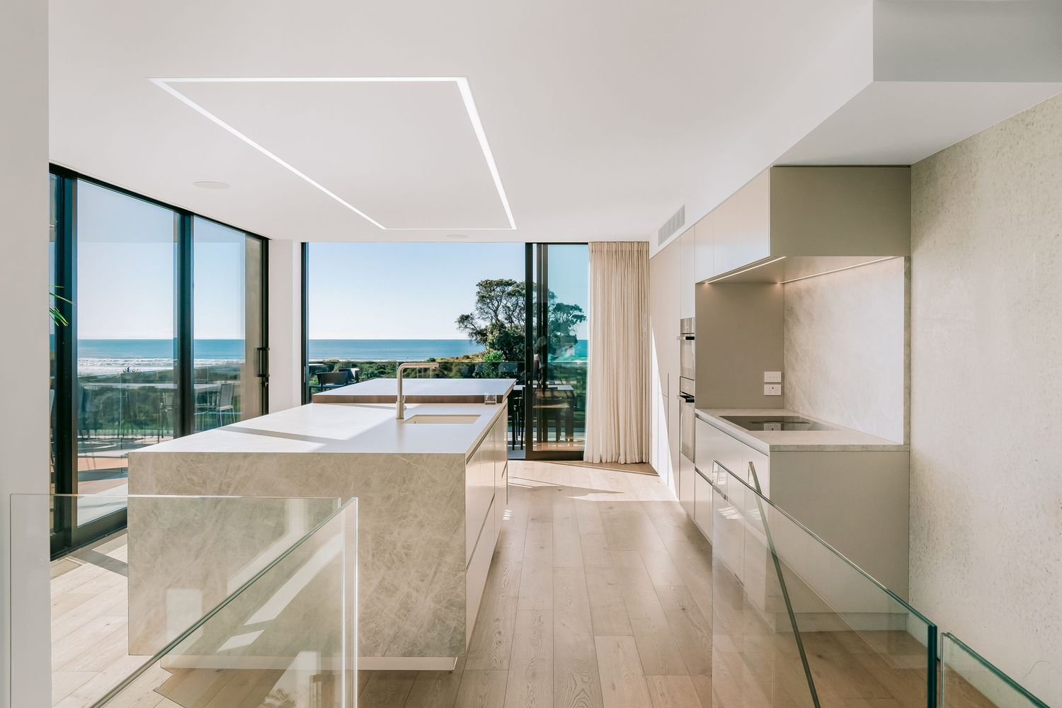 Minimalist white hallway with large windows and natural light streaming in, creating a bright contemporary living space.