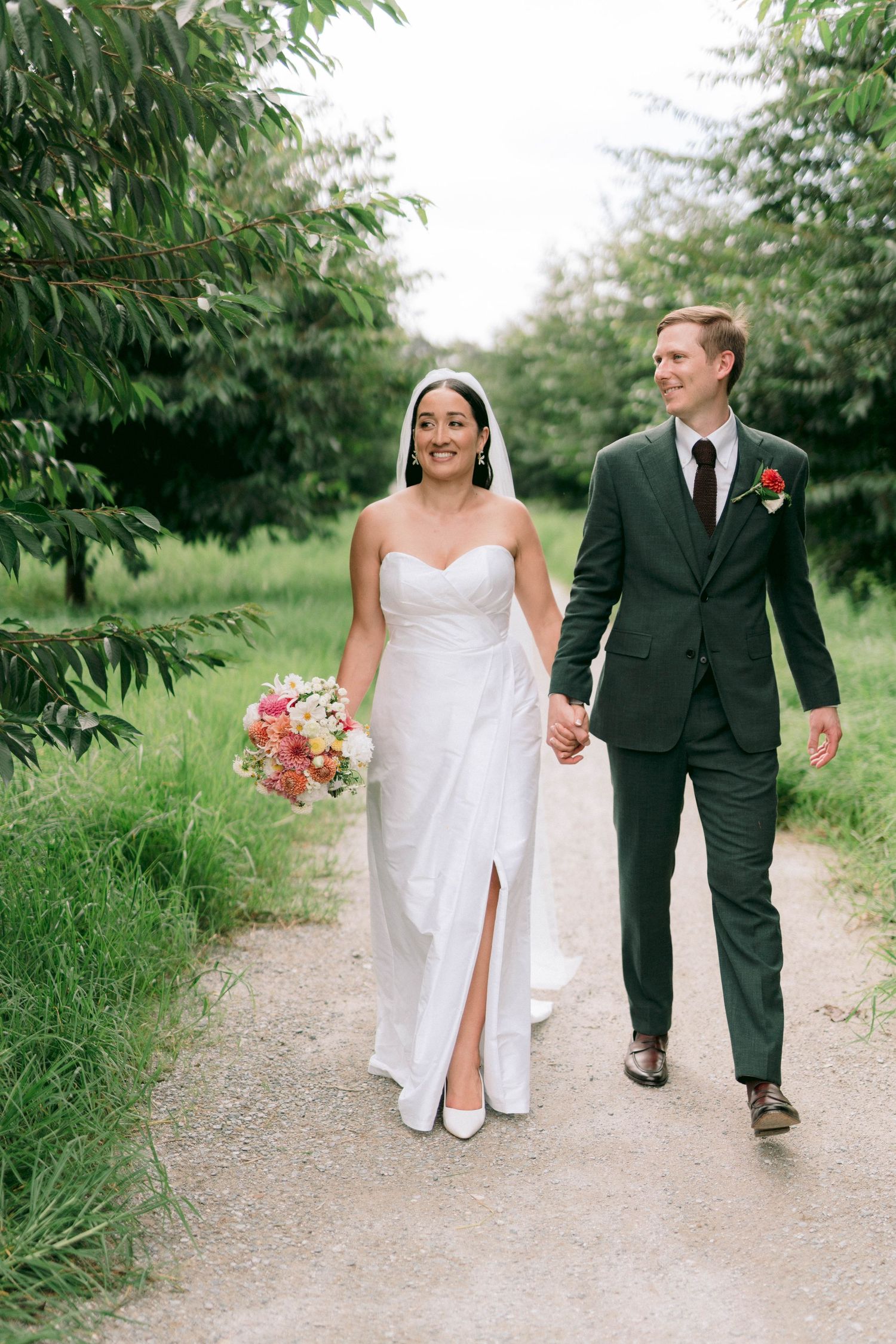 Newlyweds strolling together on a rustic garden path.