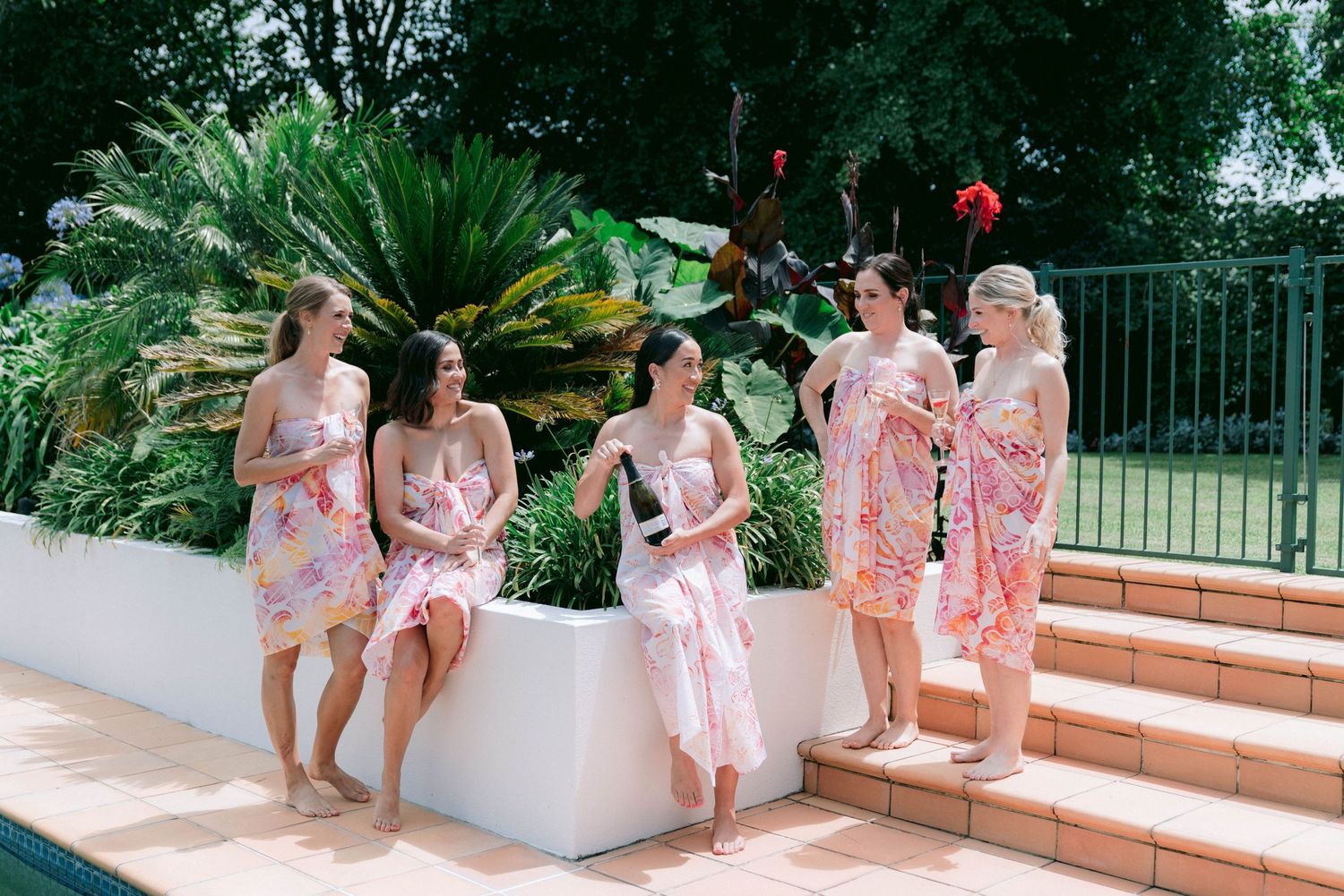 Wedding party relaxing on outdoor terrace in floral dresses.