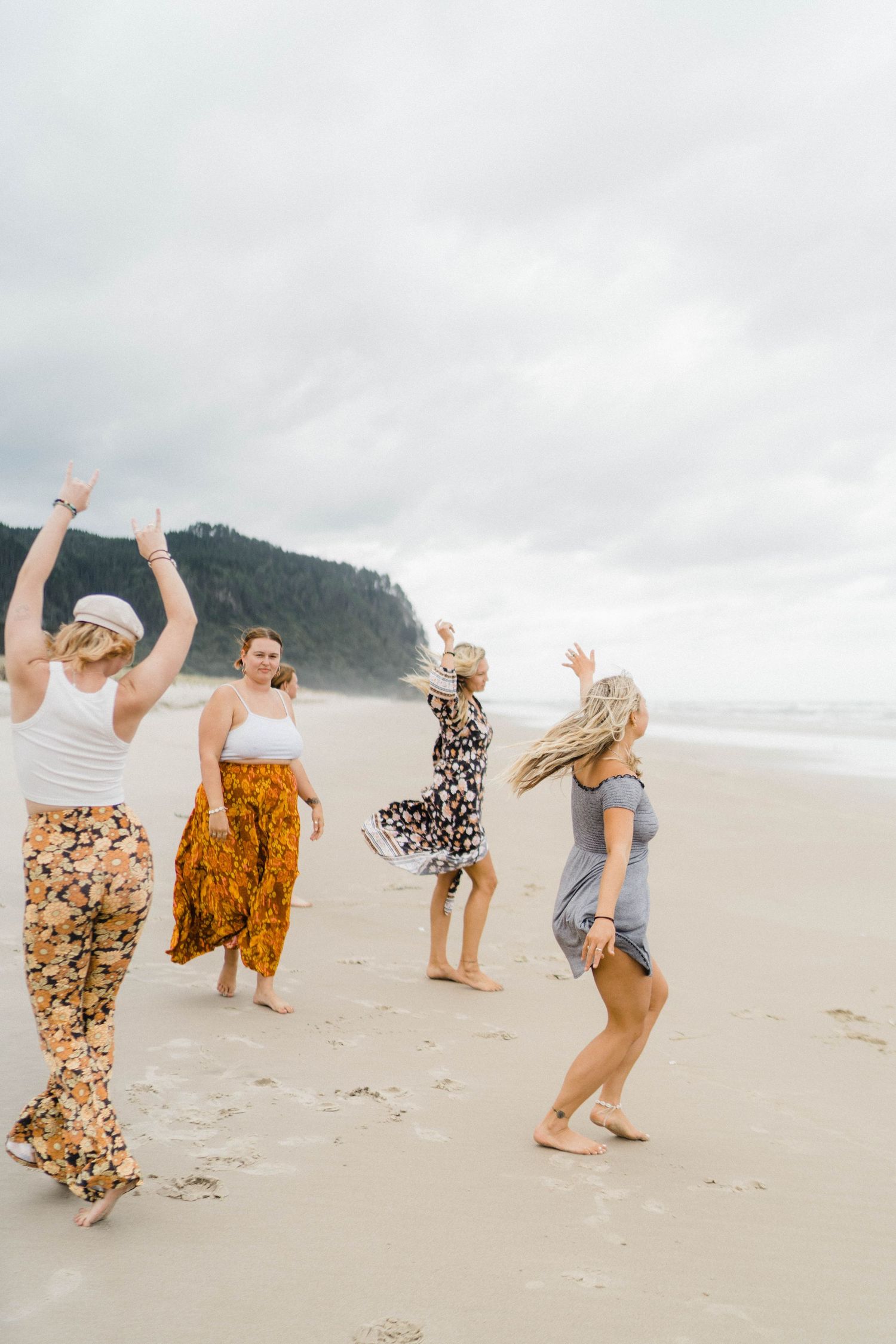 Group of friends dancing and jumping joyfully on a misty beach.