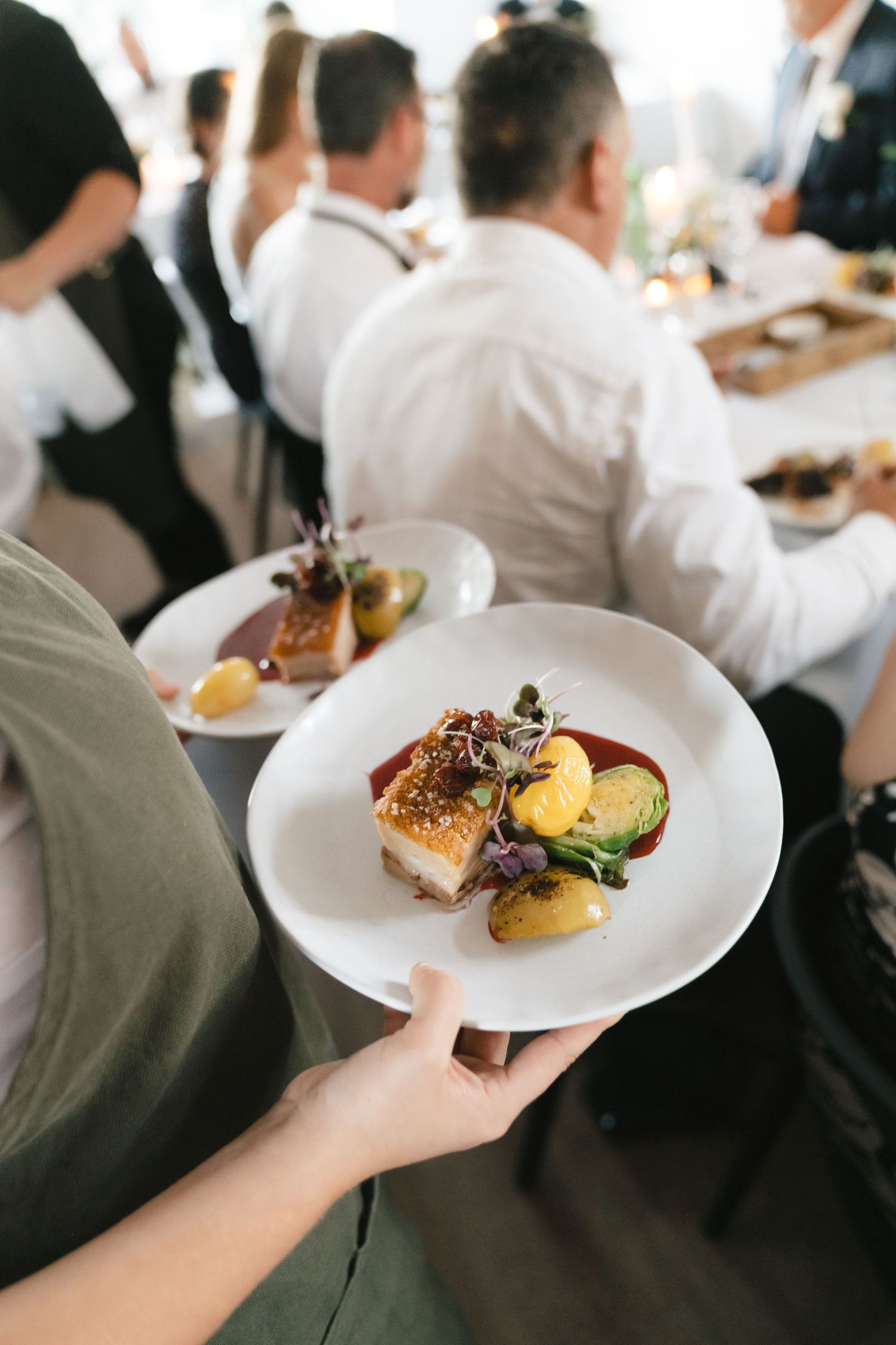 Elegant plated wedding reception meals being served on white dishes.