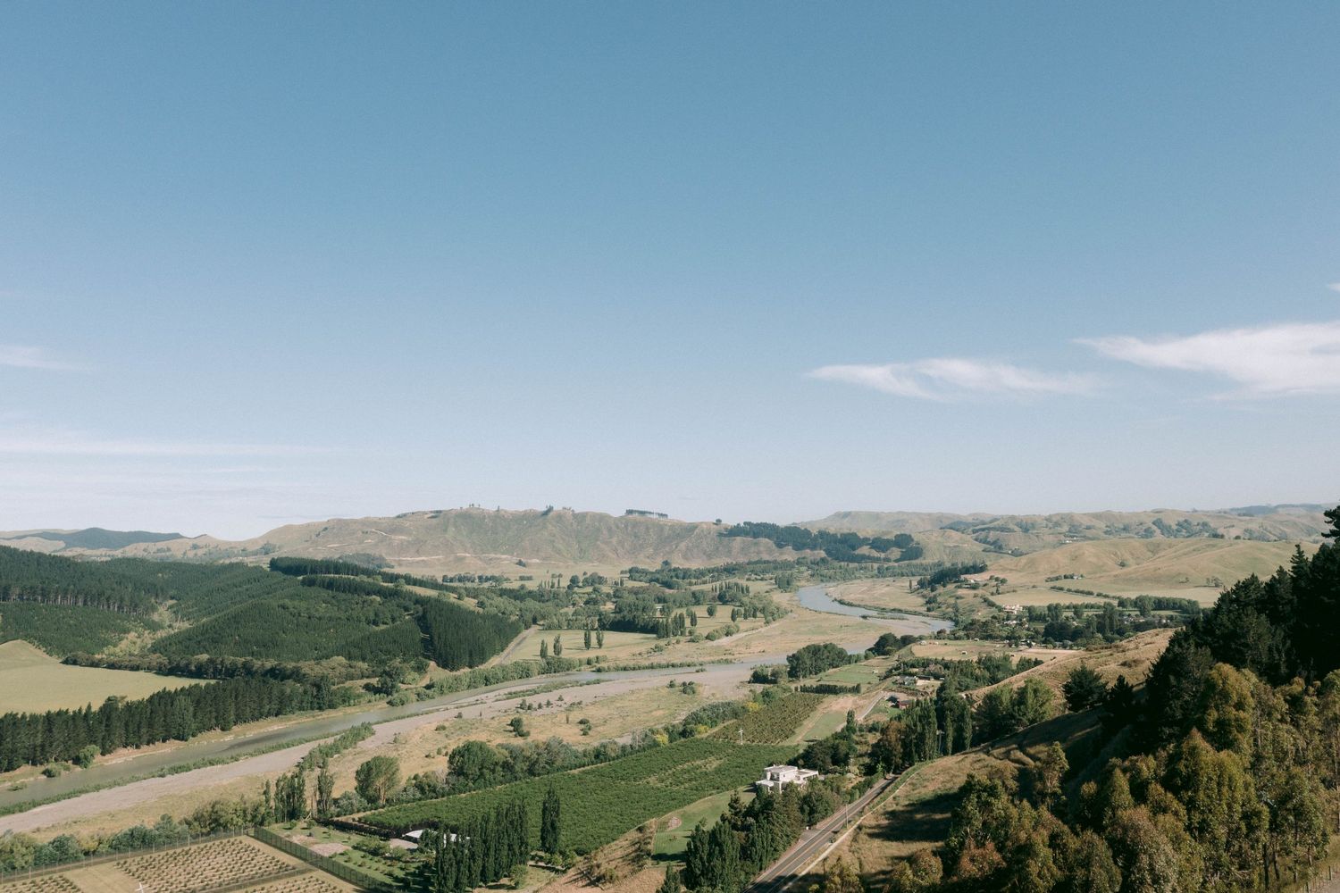 Rolling hills and valleys stretch into the distance under a bright blue sky in a scenic landscape view.