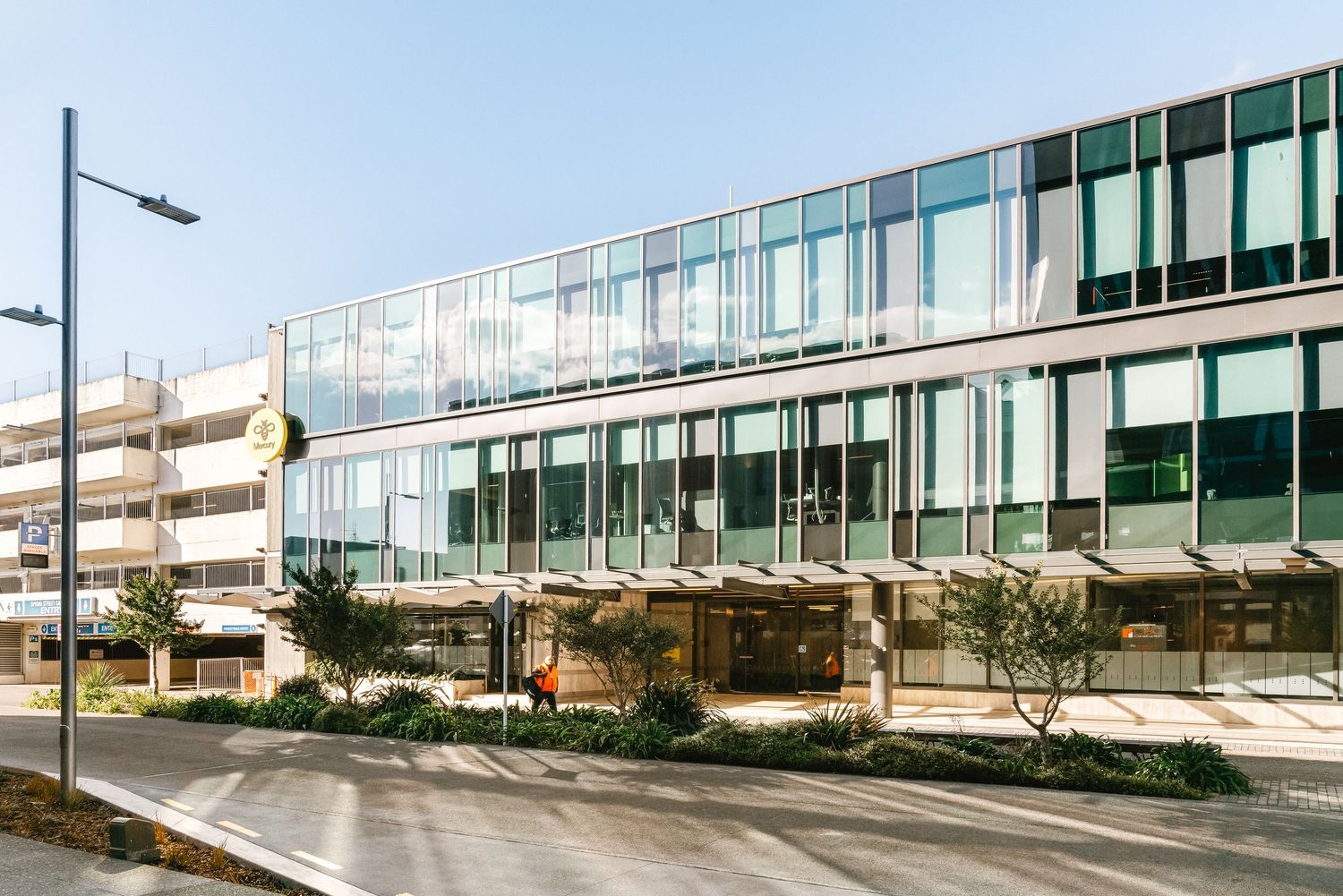 Modern office building exterior with glass facade and curved architectural design surrounded by landscaping.