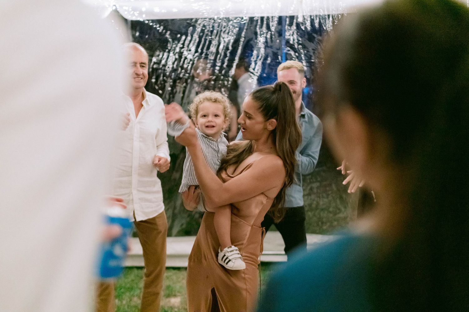 Wedding guests dancing and celebrating under string lights at an outdoor reception.