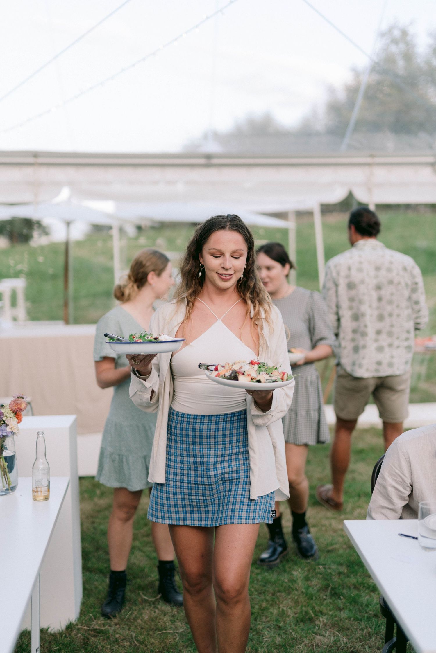 People serving food and refreshments at casual outdoor party.